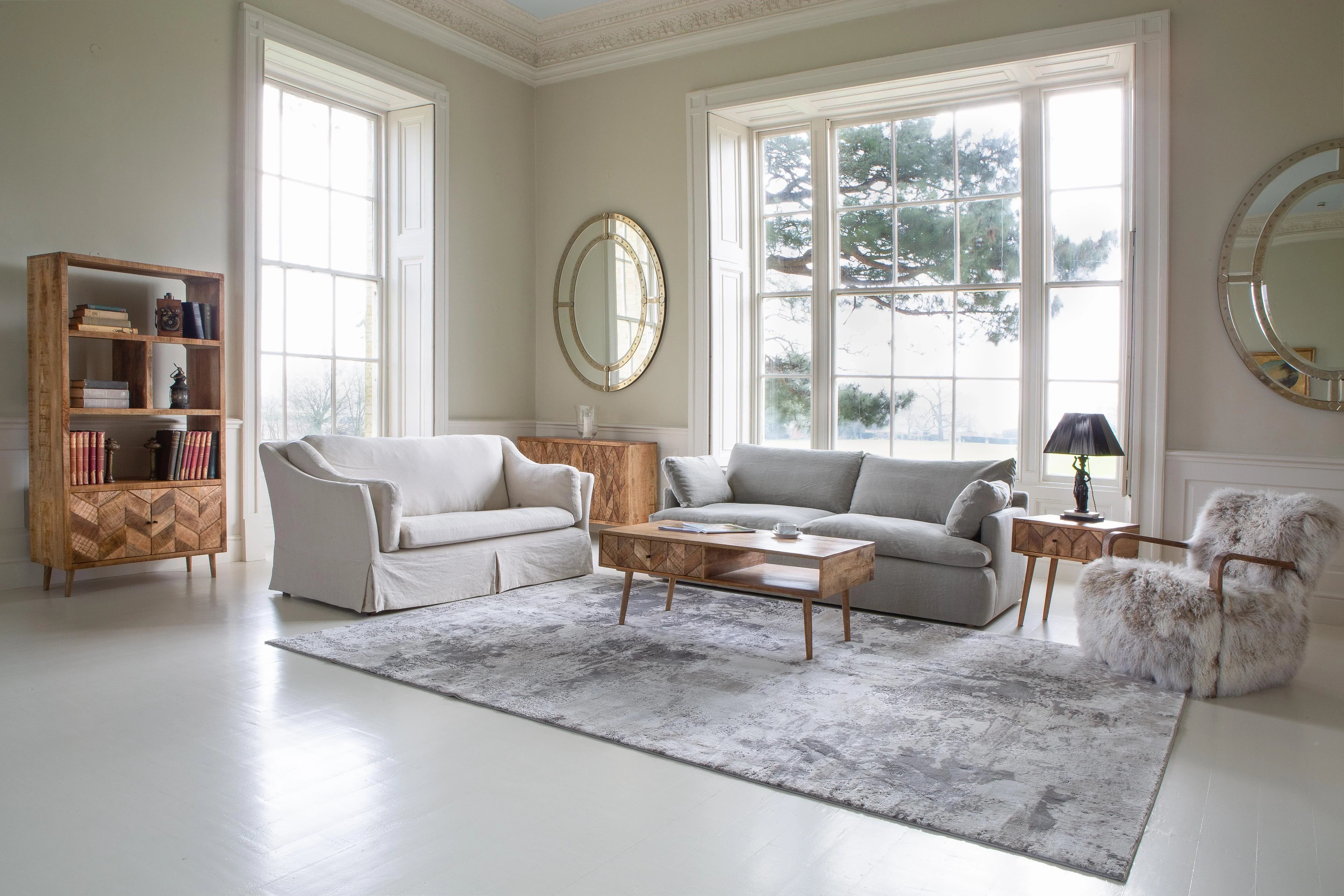 Modern living room with grey sofa, armchair, wooden coffee table and bookshelf