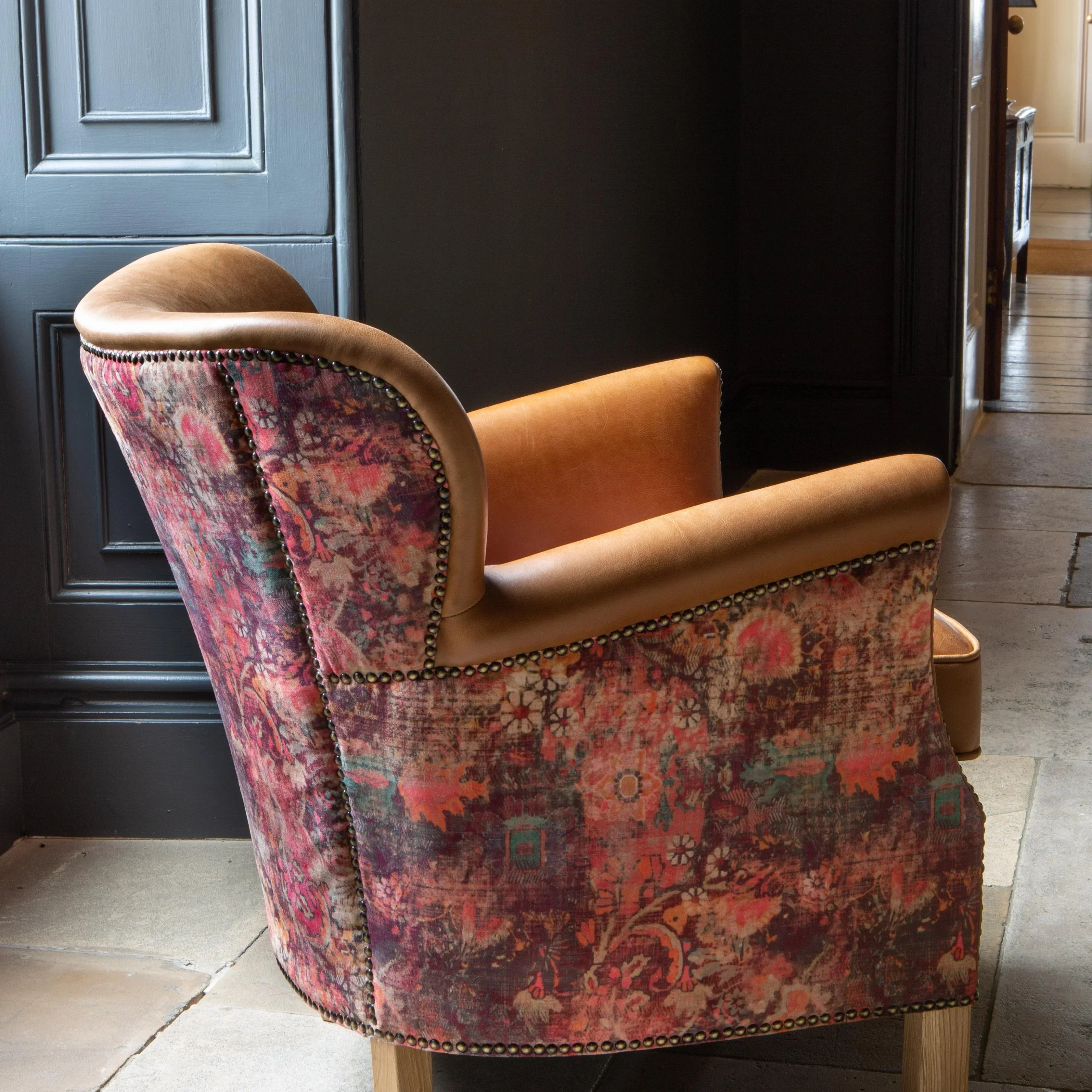 Patterned accent armchair with tan leather trim and wooden legs in a modern interior