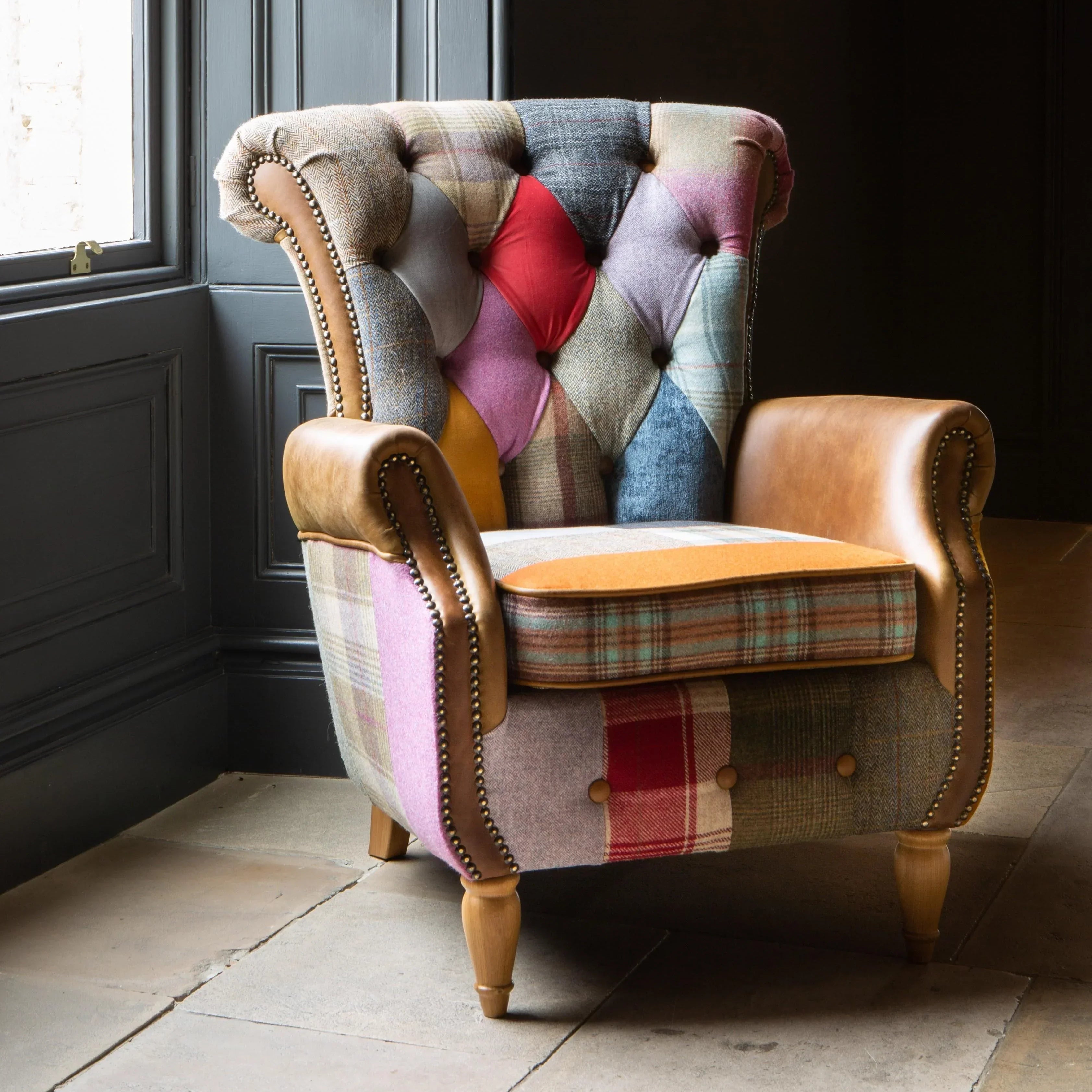 Patchwork accent armchair with button-tufted backrest and leather armrests in a bright room
