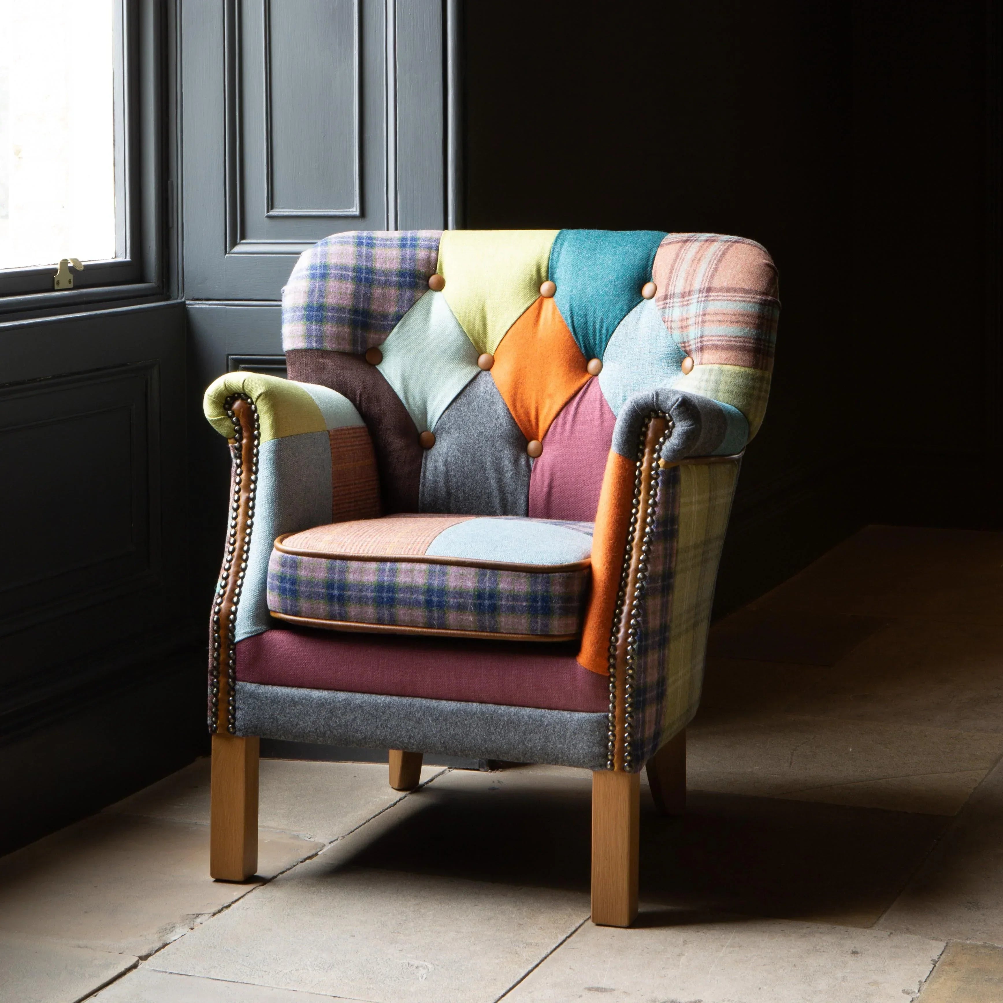 Patchwork fabric armchair with button detail and wooden legs near a window