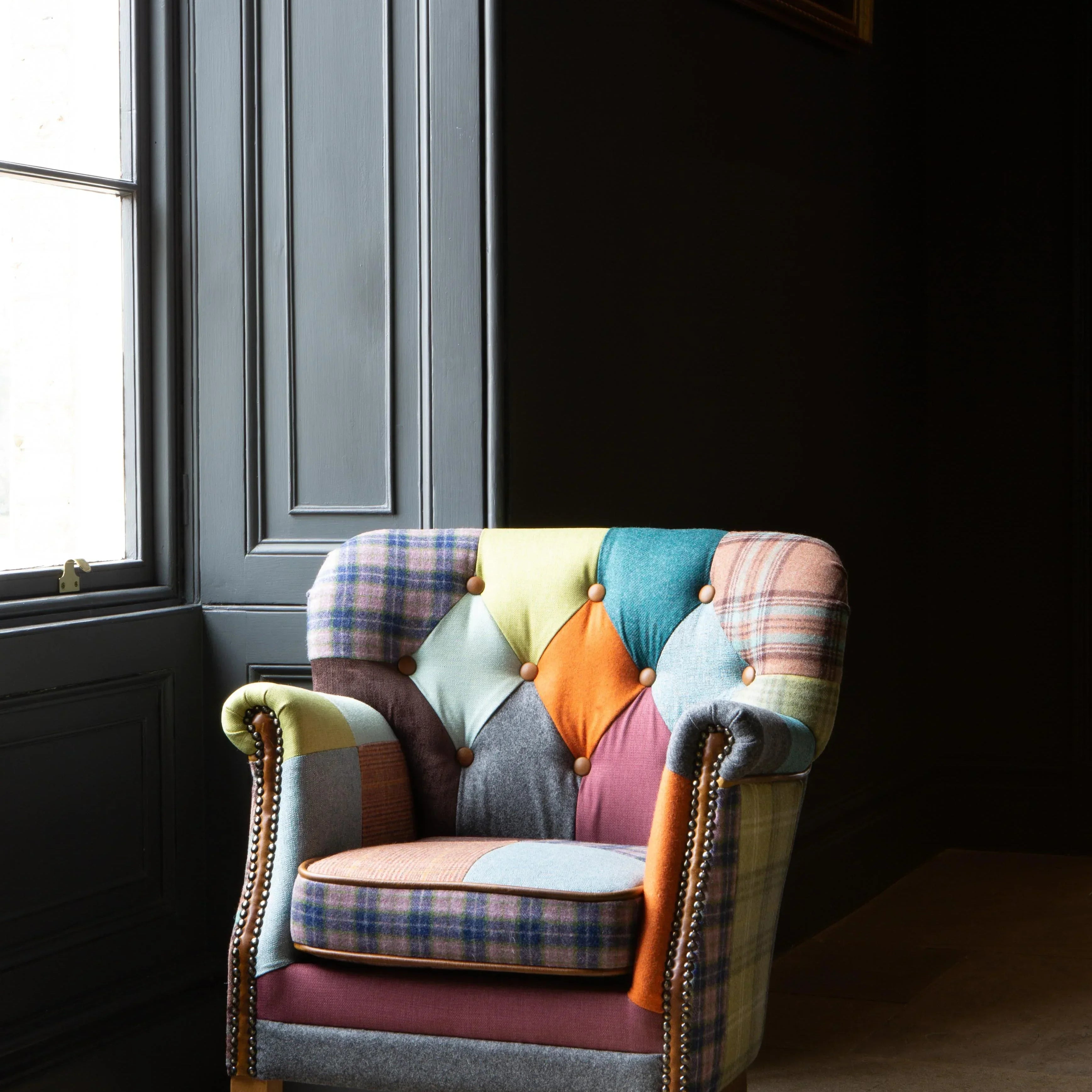 Patchwork accent armchair with wooden legs beside tall window on tiled floor