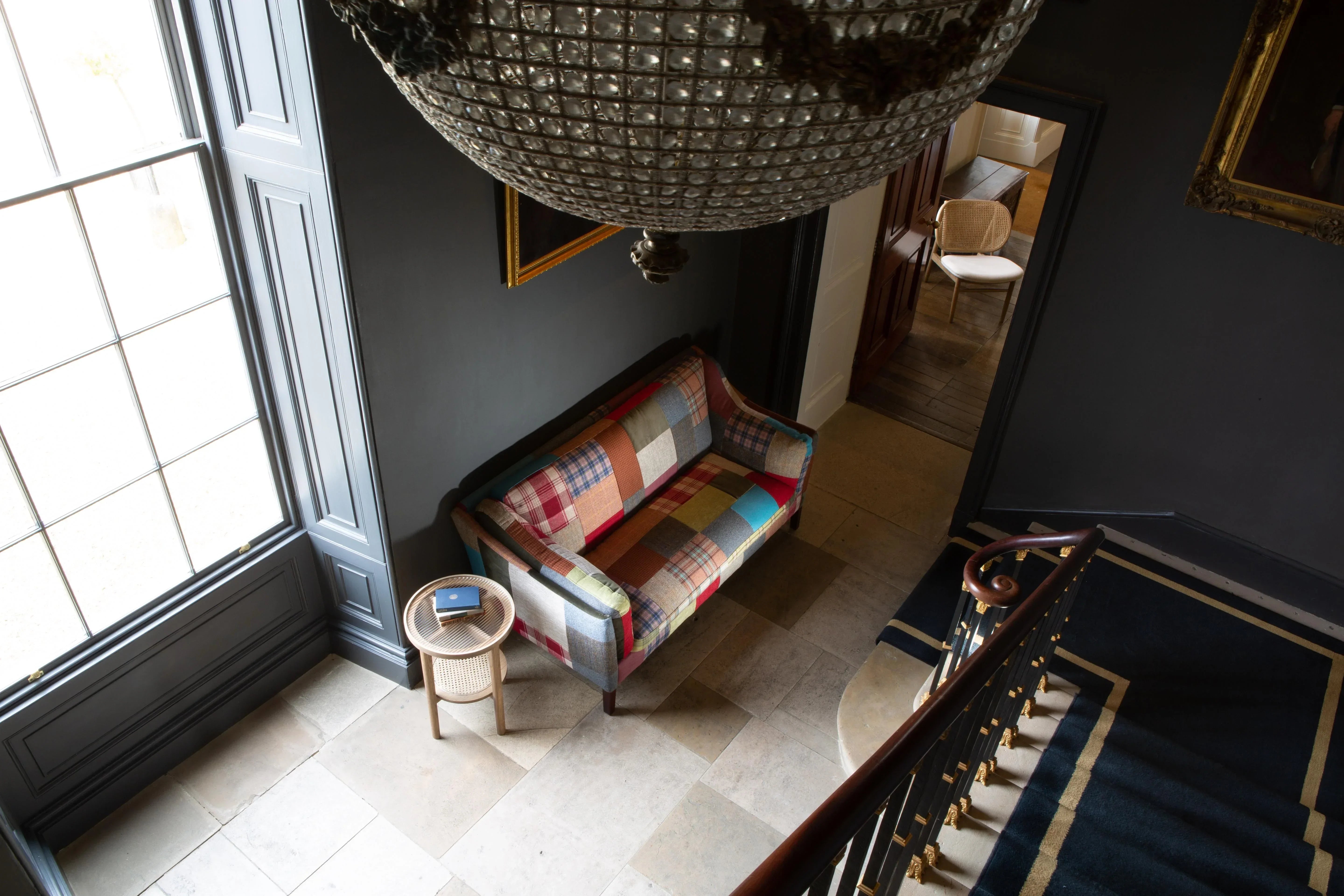 Patchwork fabric sofa with wooden legs in hallway, beside a round rattan side table