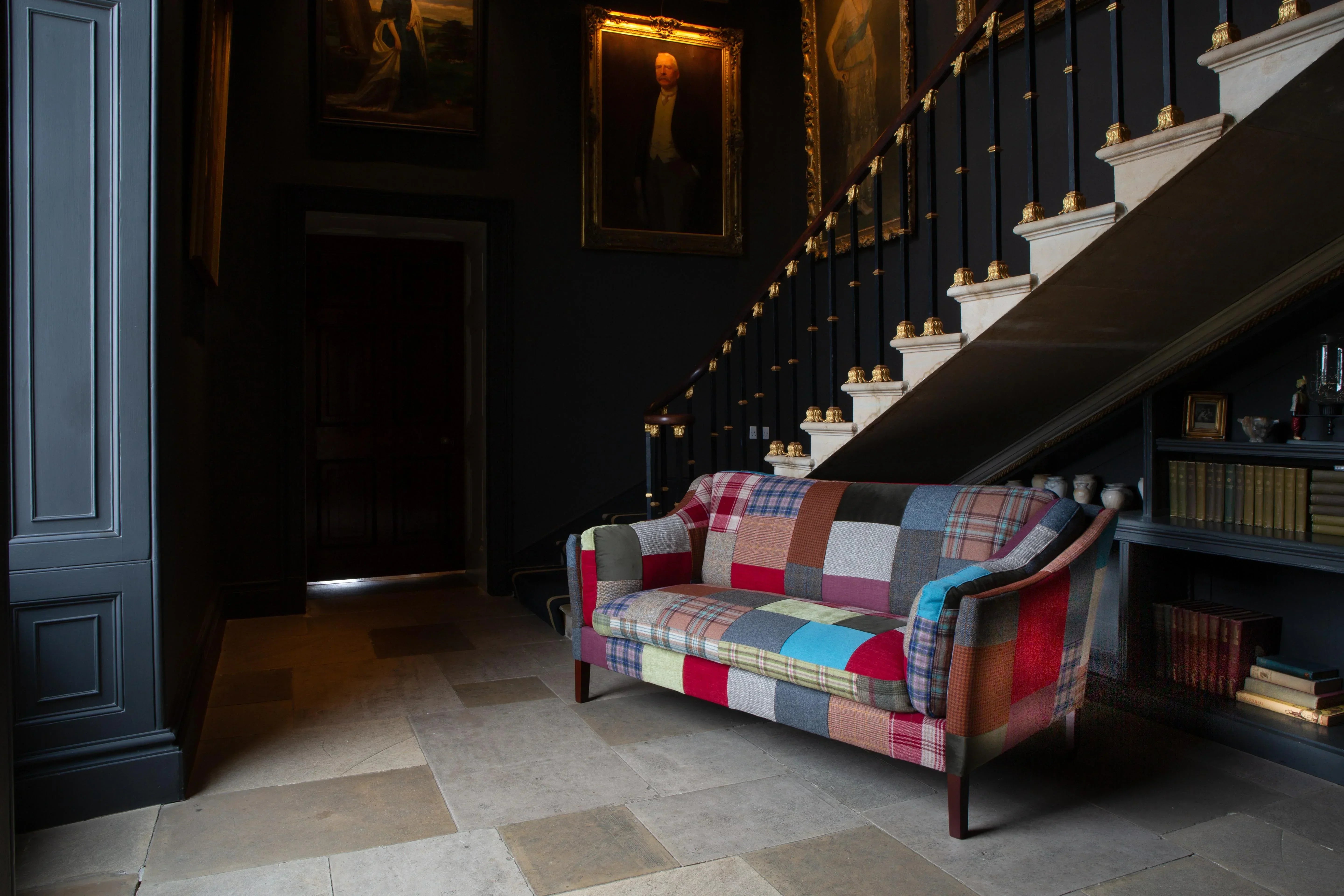 Patchwork fabric sofa in hallway with tiled floor and staircase