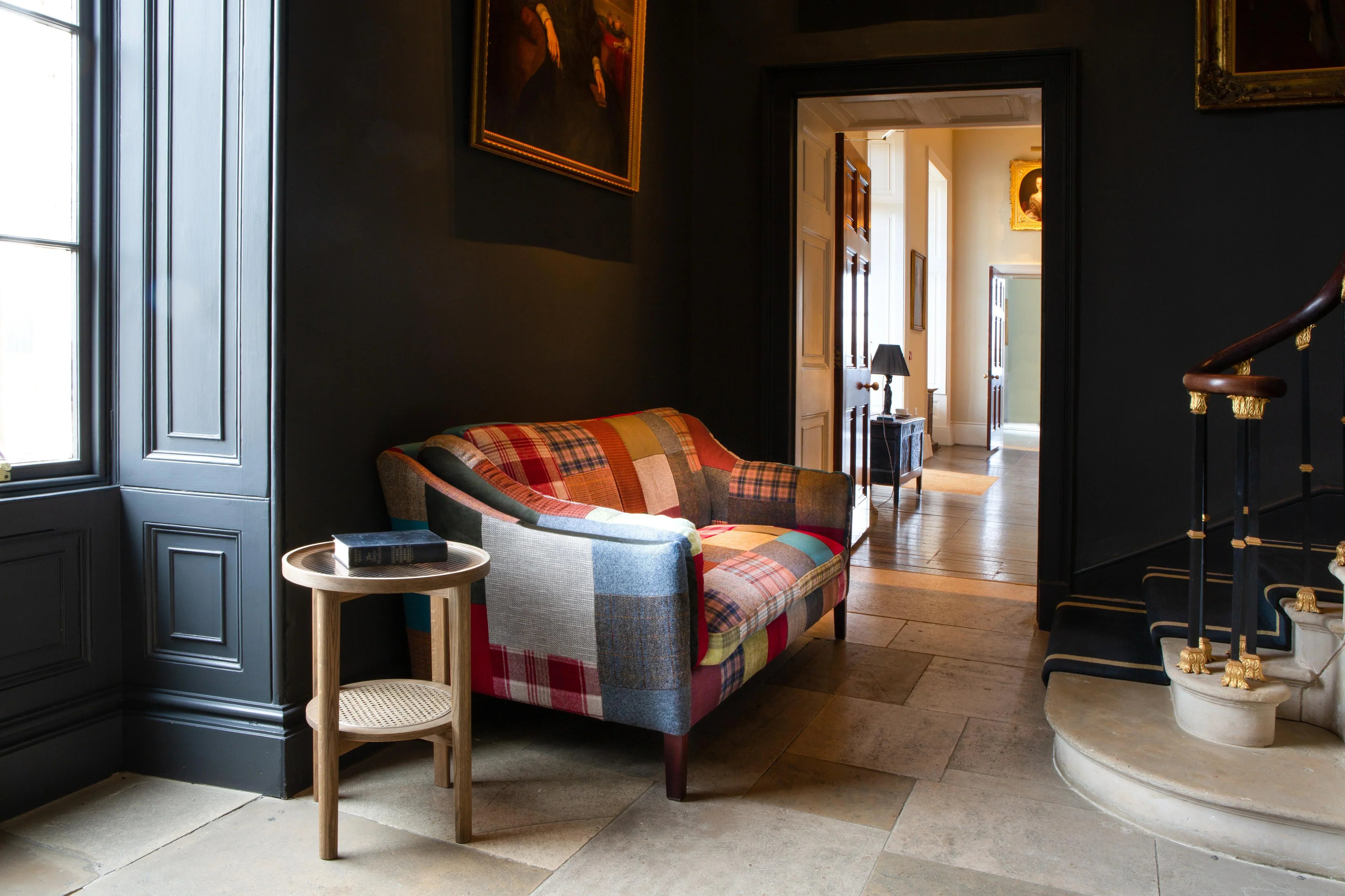 Patchwork fabric sofa with wooden legs in classic hallway beside round side table