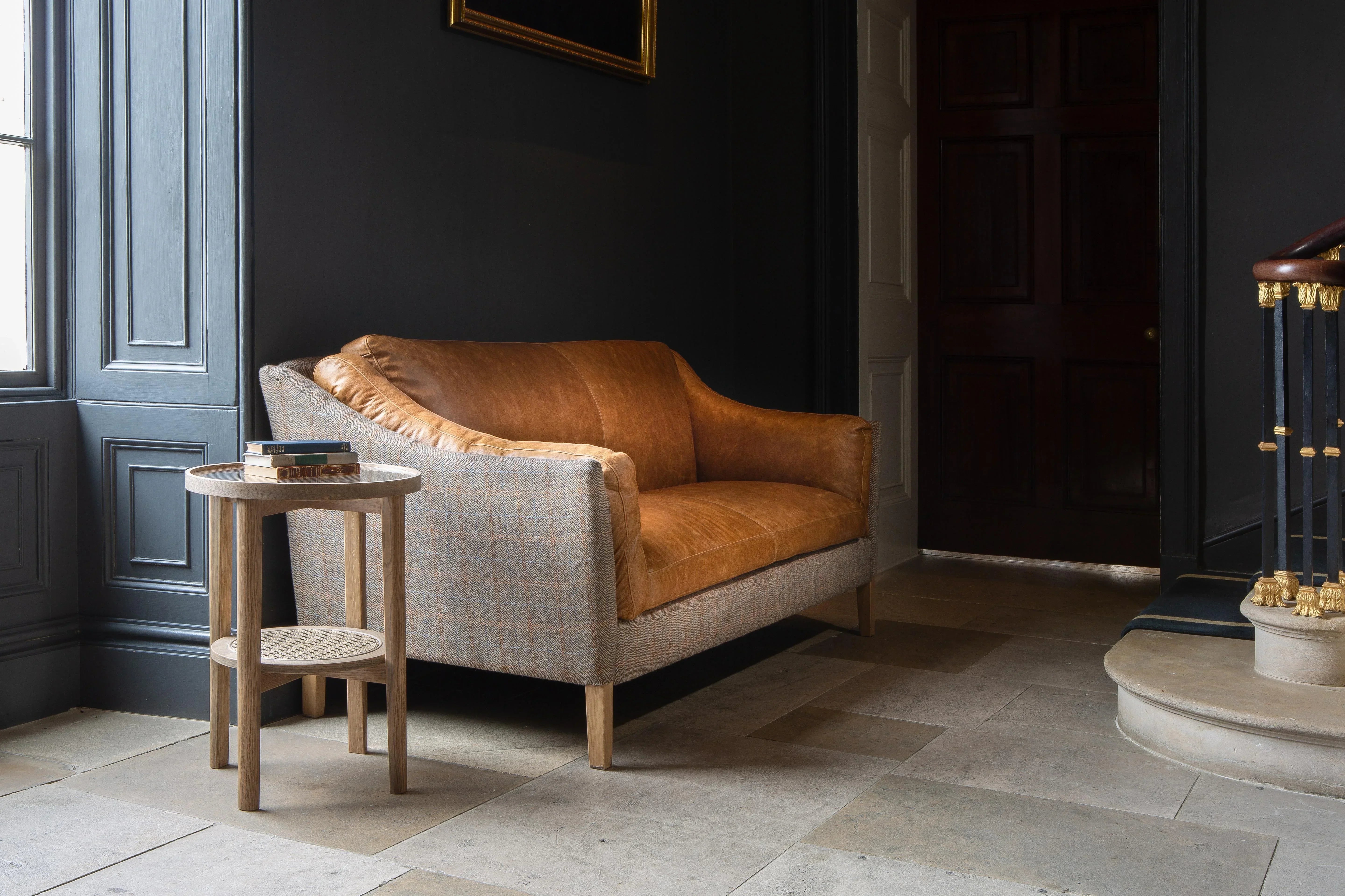 Tan leather and tweed two-seater sofa with wooden side table in hallway