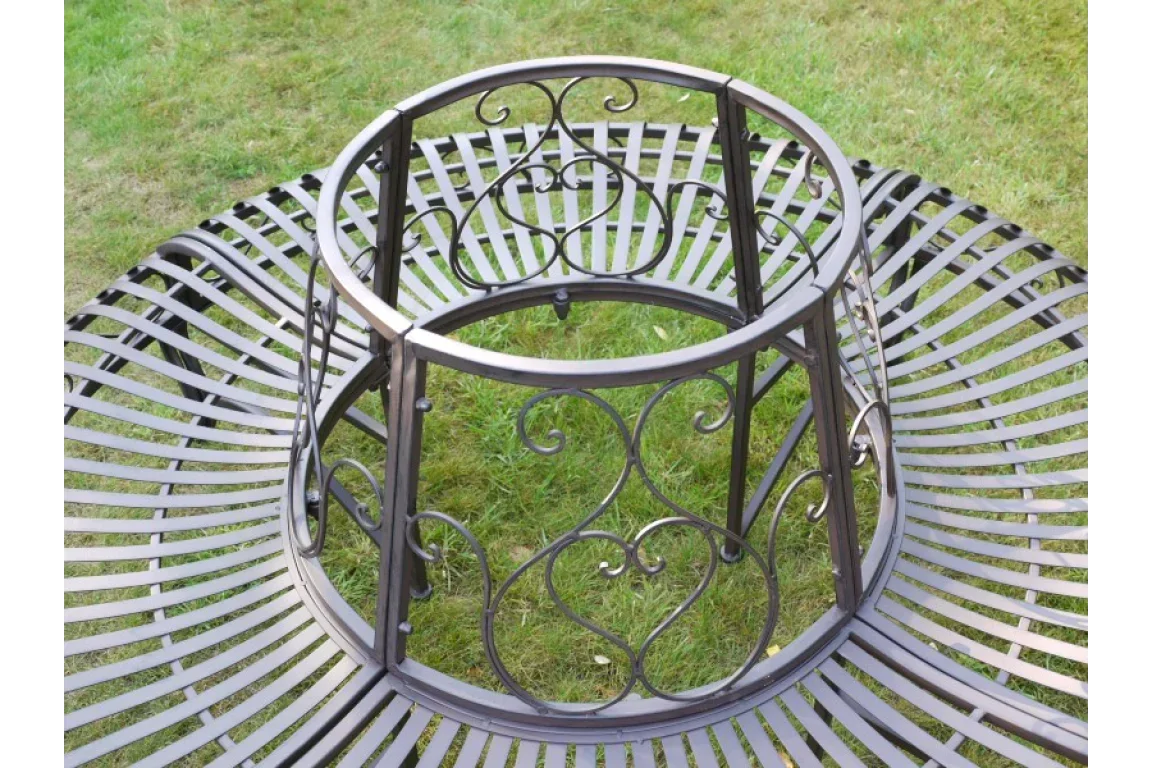 Black metal tree bench with decorative scrollwork set on green garden lawn