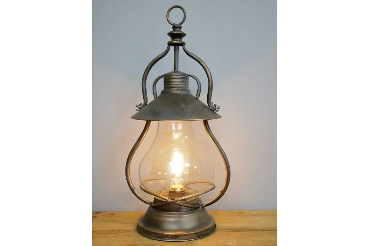 Vintage metal table lamp with clear glass shade on wooden surface