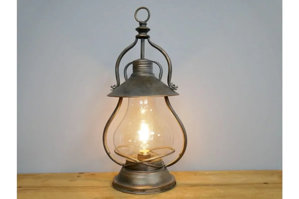 Vintage metal table lamp with clear glass shade on wood surface