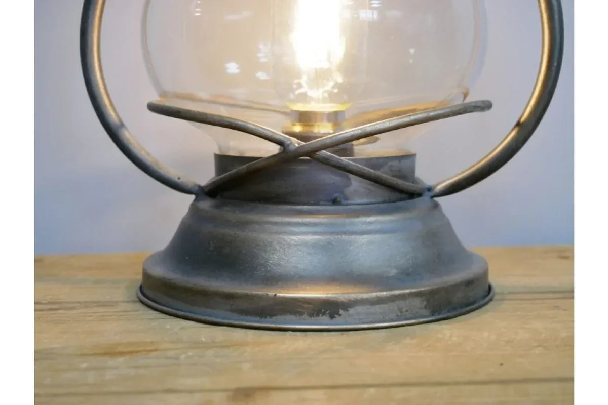 Vintage metal lantern lamp with glass shade on wooden surface, rustic decor lighting
