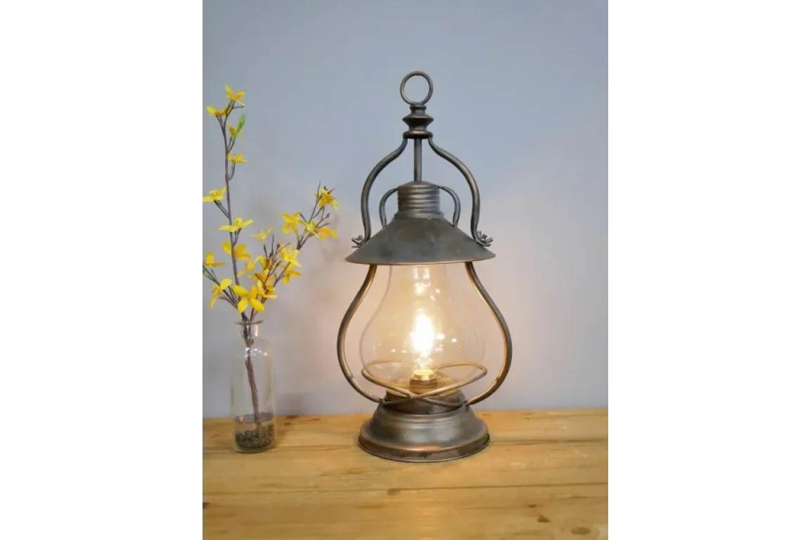 Vintage metal table lamp with glass shade on wooden surface, yellow flowers in vase