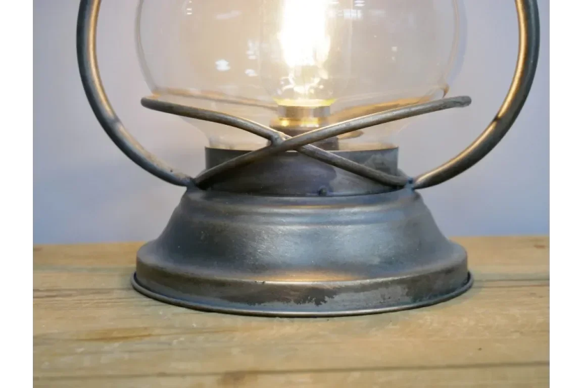 Close-up of vintage metal table lamp base with glass shade on wooden surface