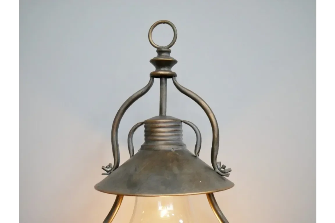 close-up of vintage metal pendant light with glass shade against grey background