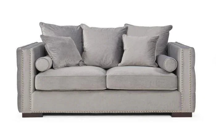 Grey velvet sofa with studded arms, matching scatter cushions, and wooden feet, front view