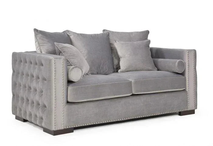 Grey velvet sofa with button-tufted arms, silver stud trim and plush scatter cushions