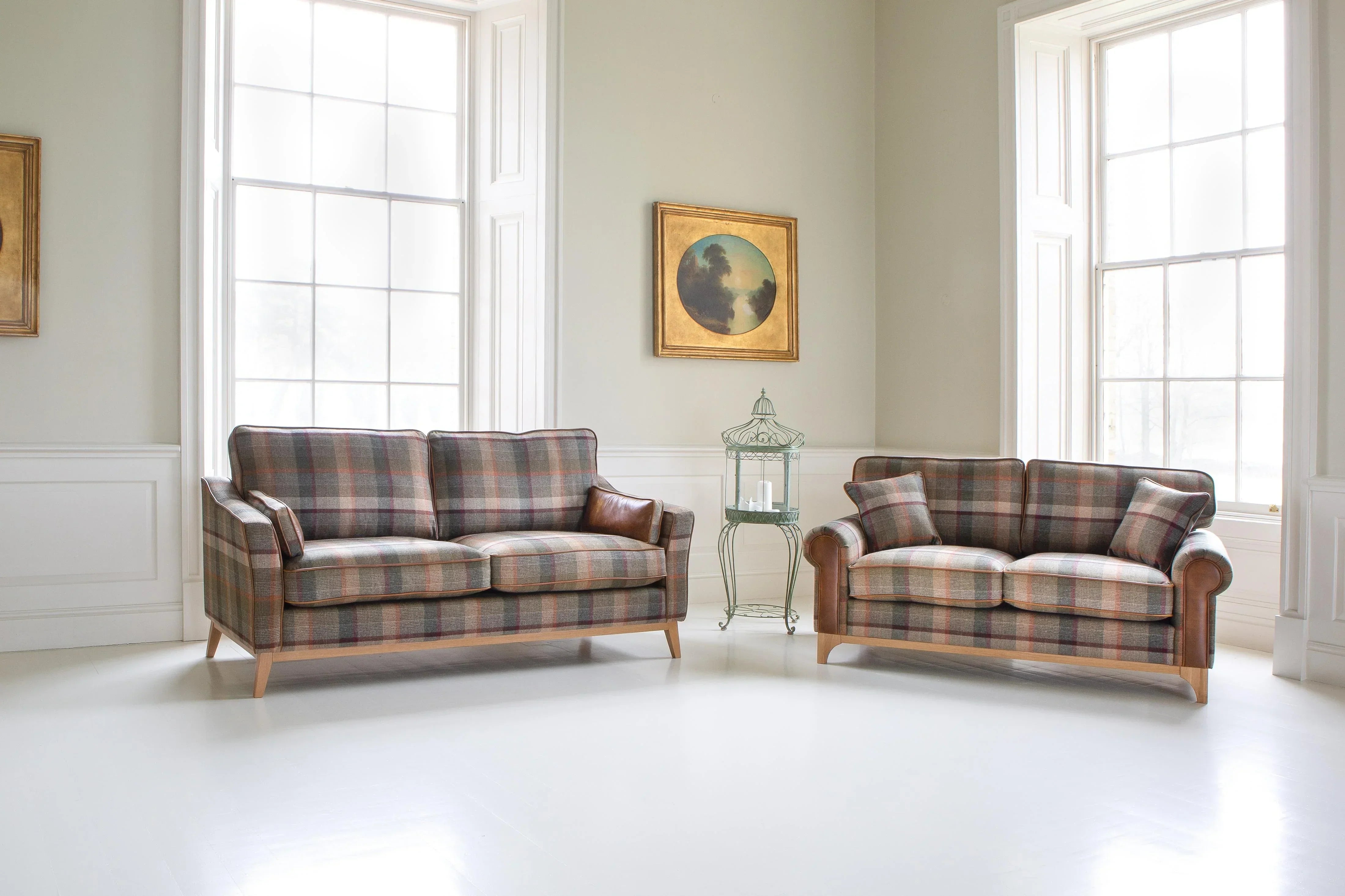 Plaid fabric sofas with wooden legs in bright living room with large windows and wall art