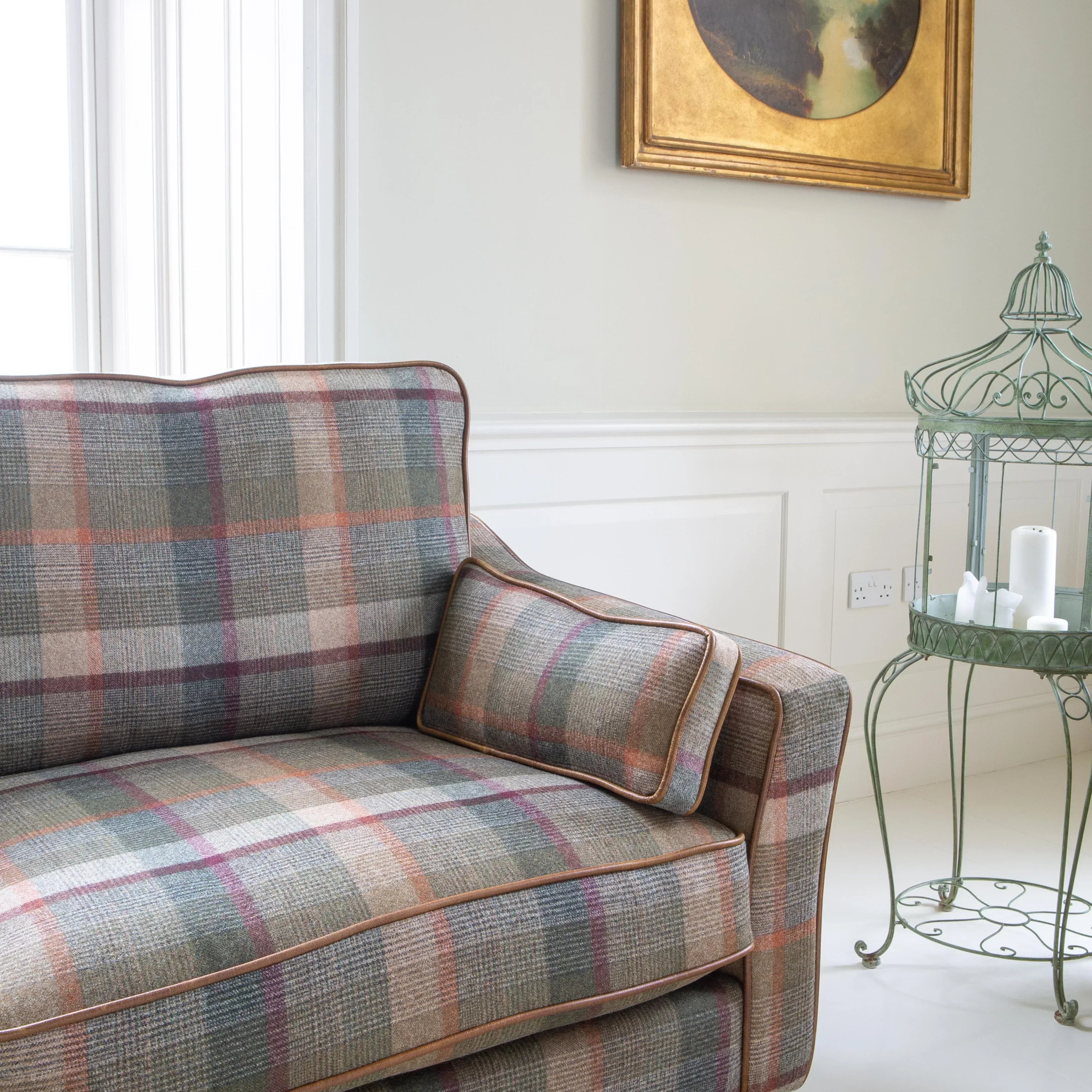 Plaid fabric sofa with wooden legs in bright living room, side table and wall art