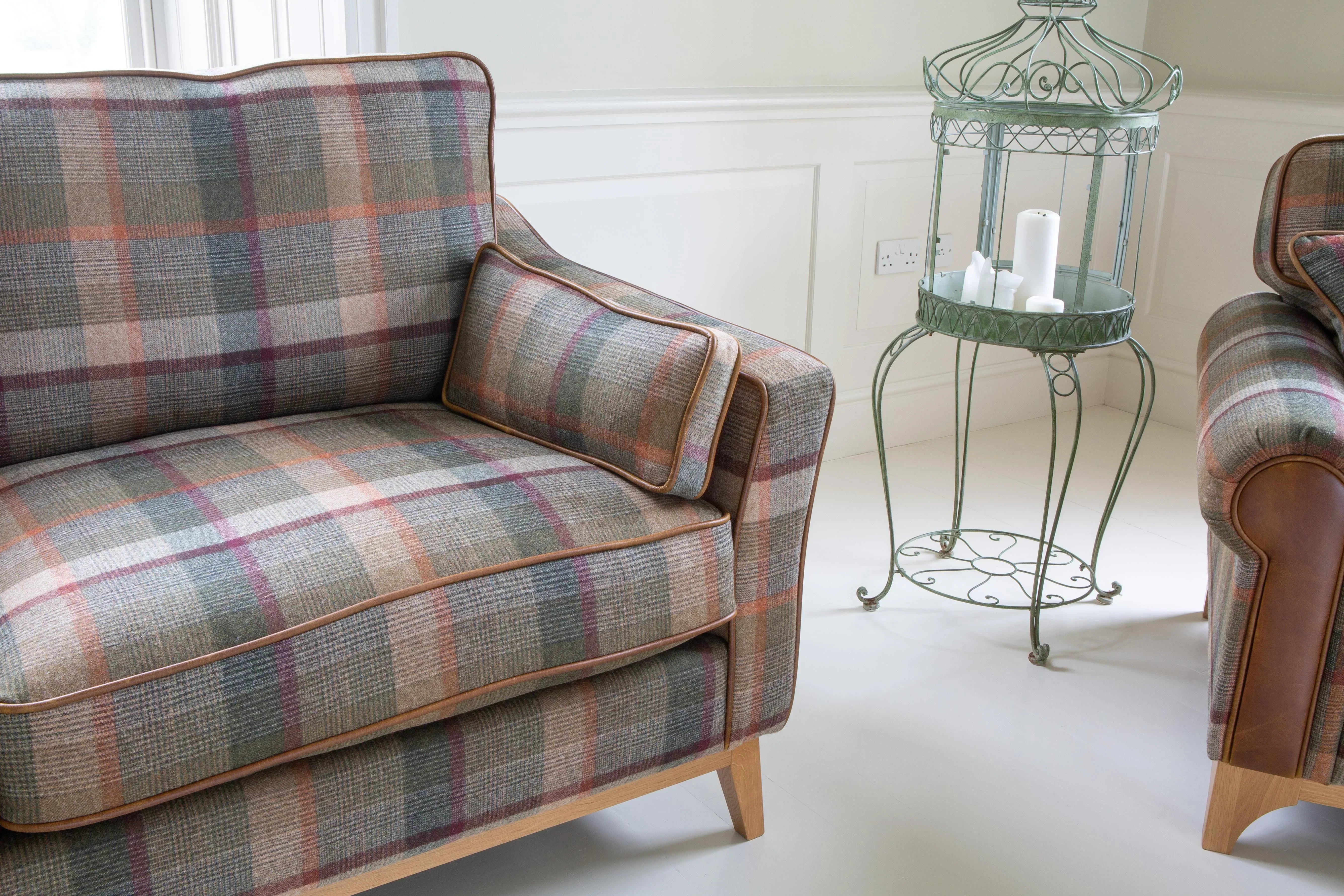 Plaid fabric armchair with wooden legs and matching cushion beside metal candle stand