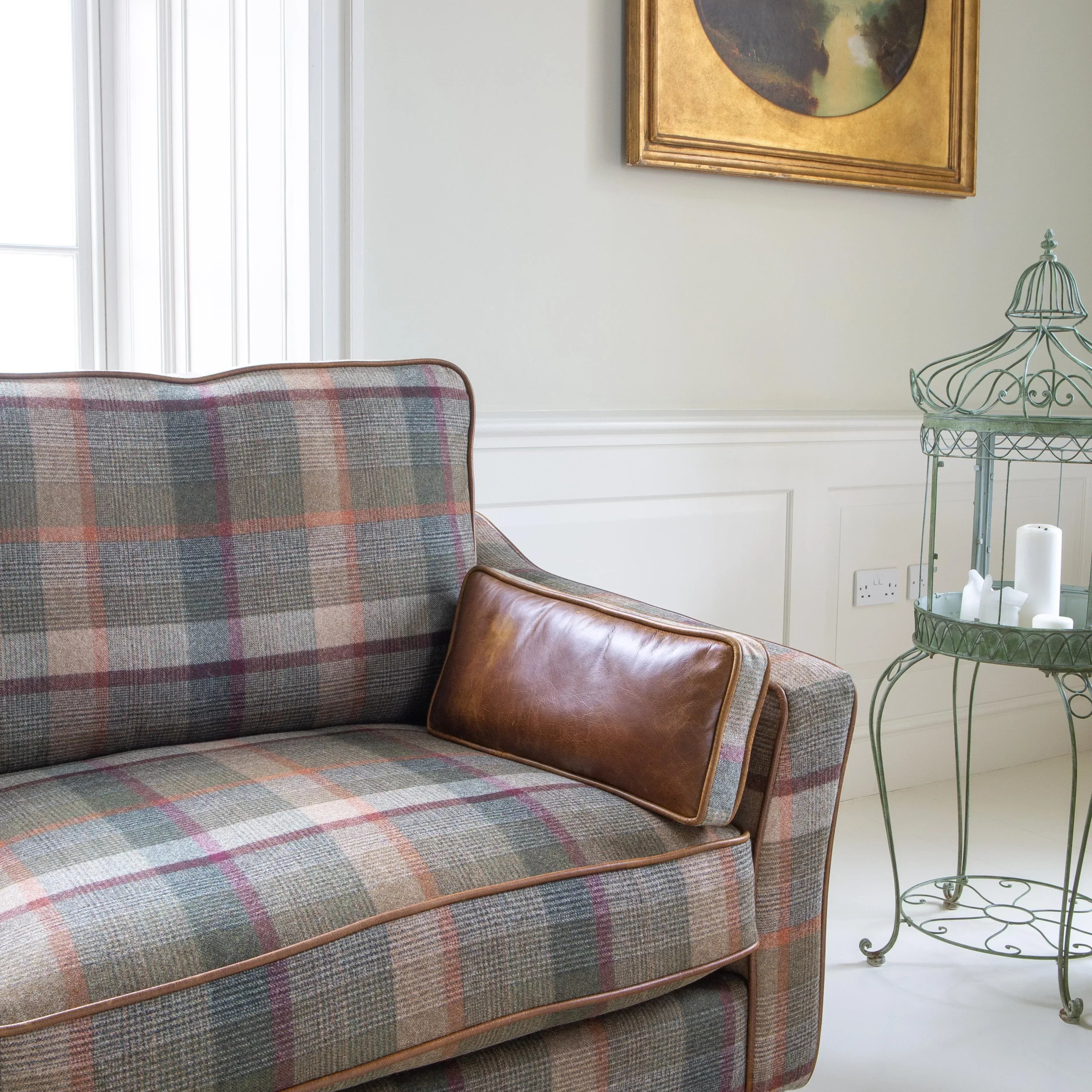Plaid upholstered sofa with leather cushion in bright lounge, next to metal side table
