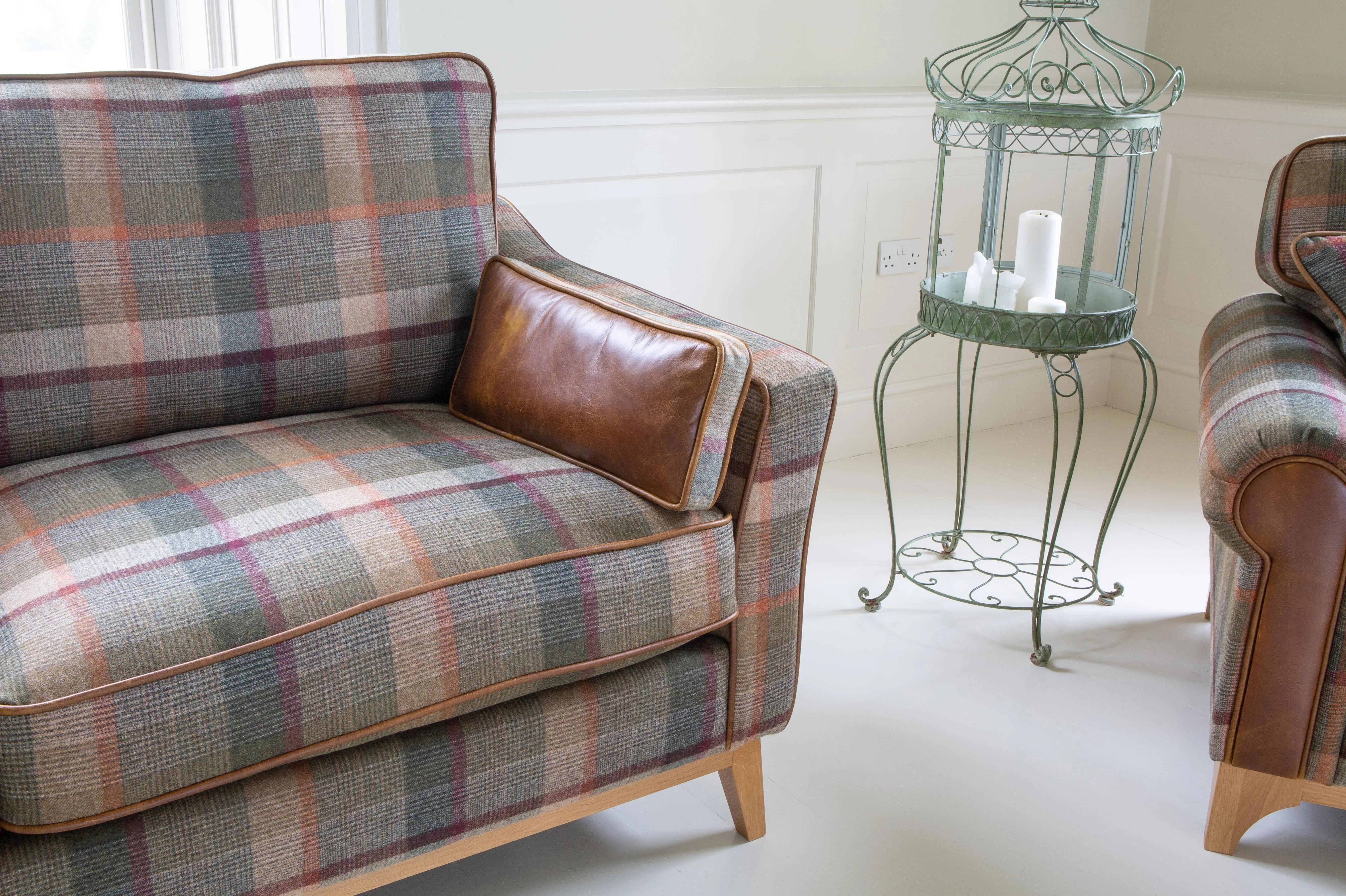 Plaid fabric sofa with brown leather cushion and wooden legs in bright living room