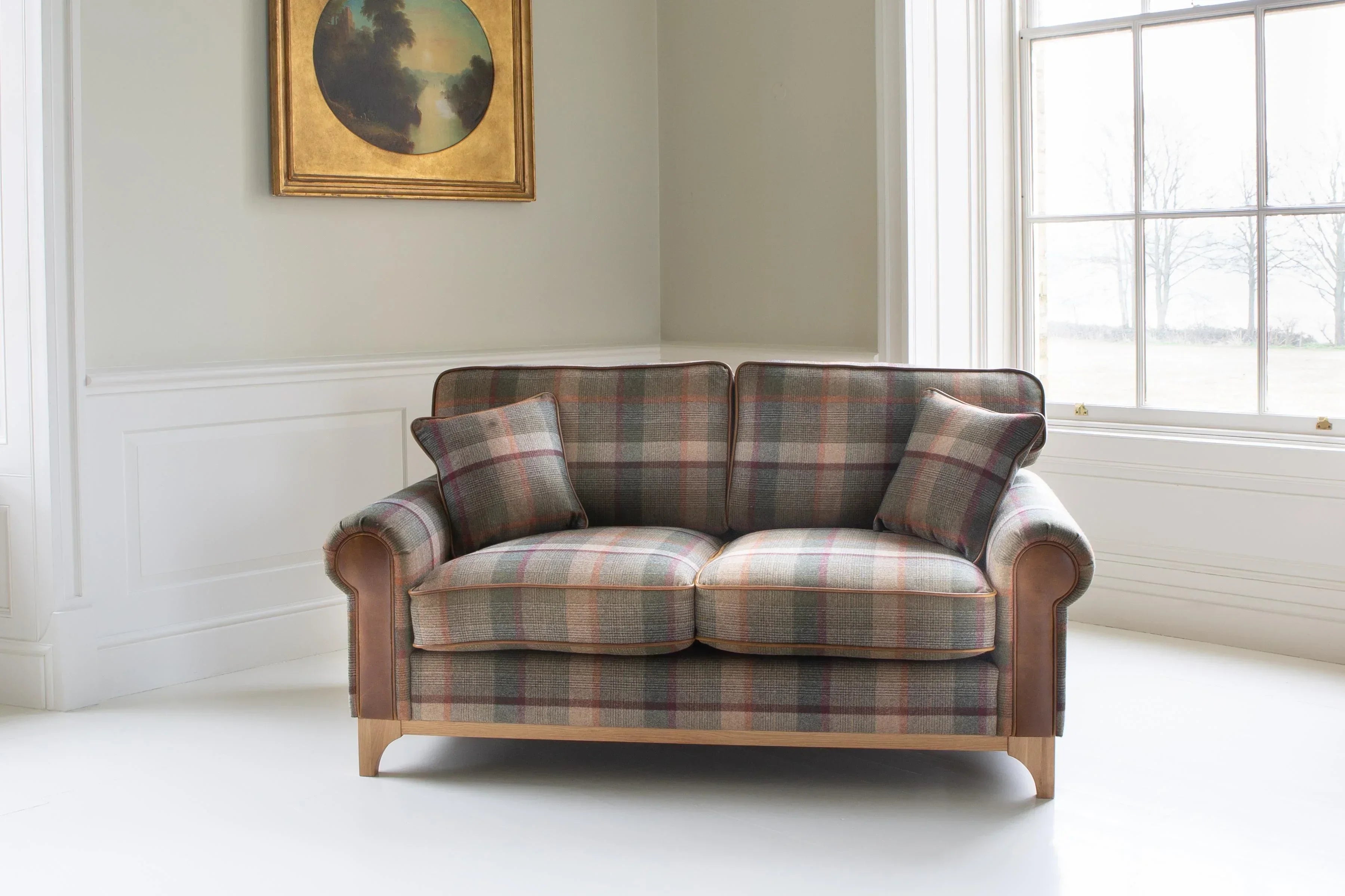 Plaid fabric two-seater sofa with matching cushions in bright living room setting