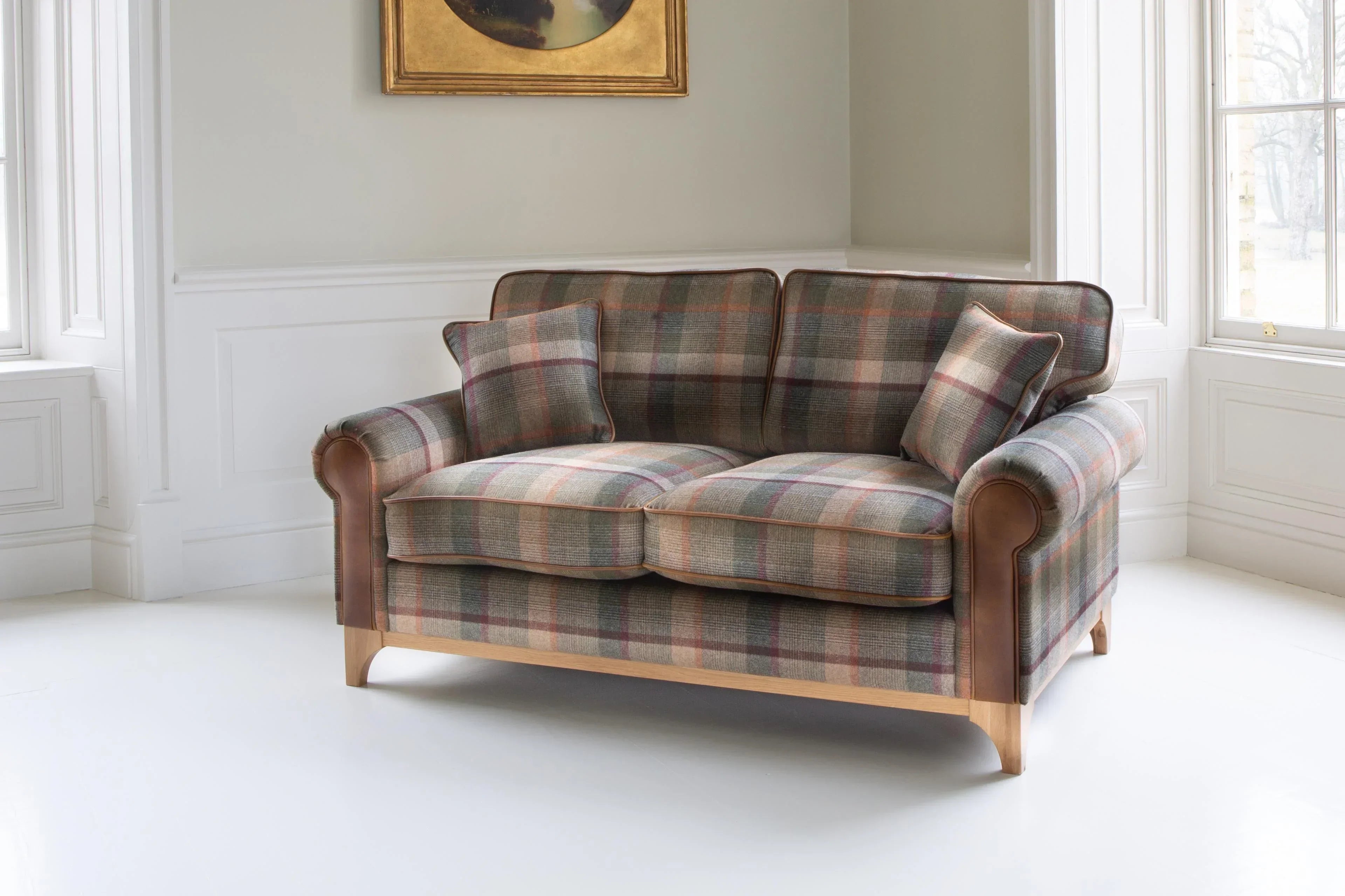 Plaid fabric sofa with wooden legs and leather arm accents in bright living room