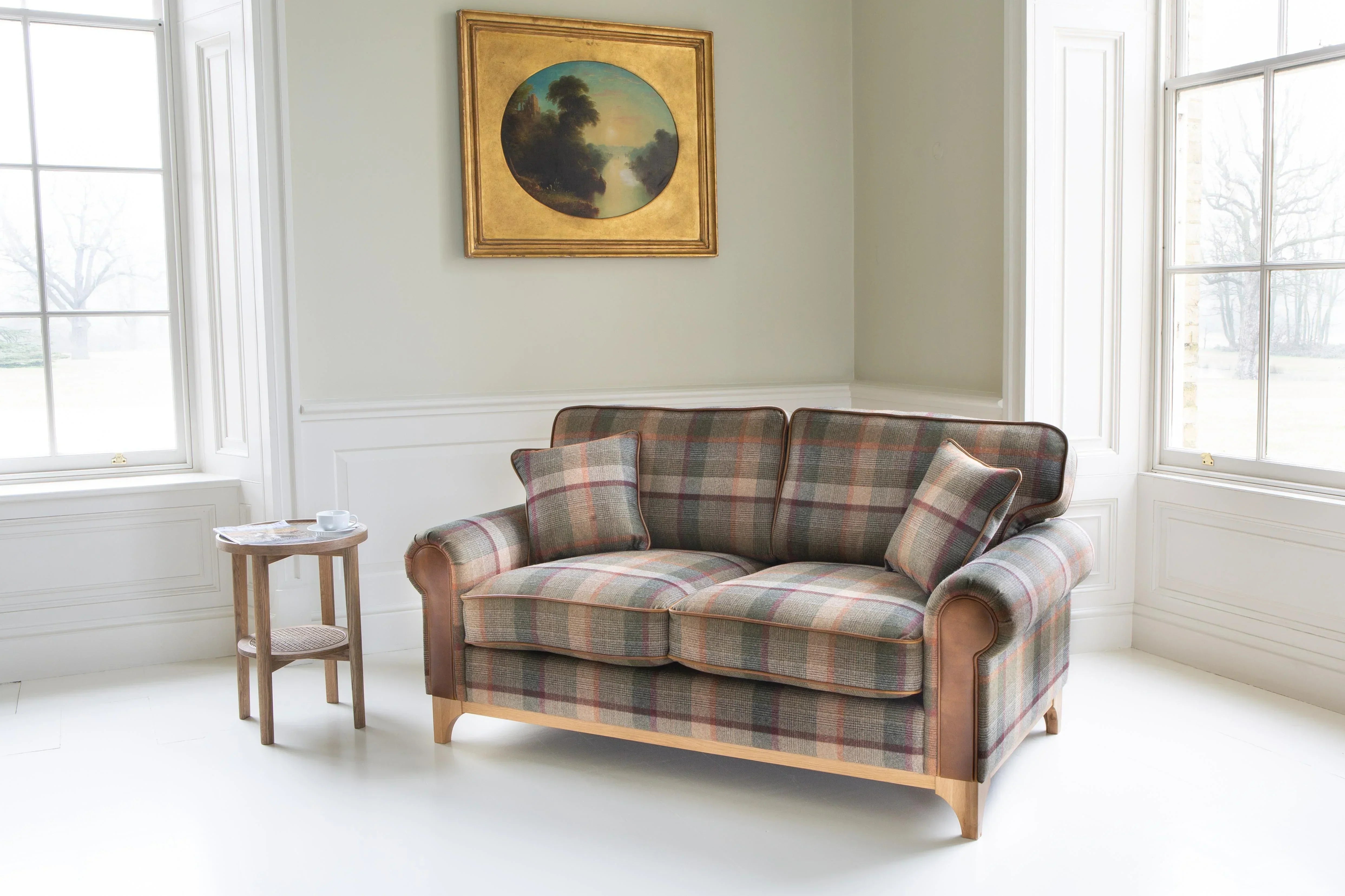 Plaid fabric sofa with wooden legs in bright living room, paired with a small round side table