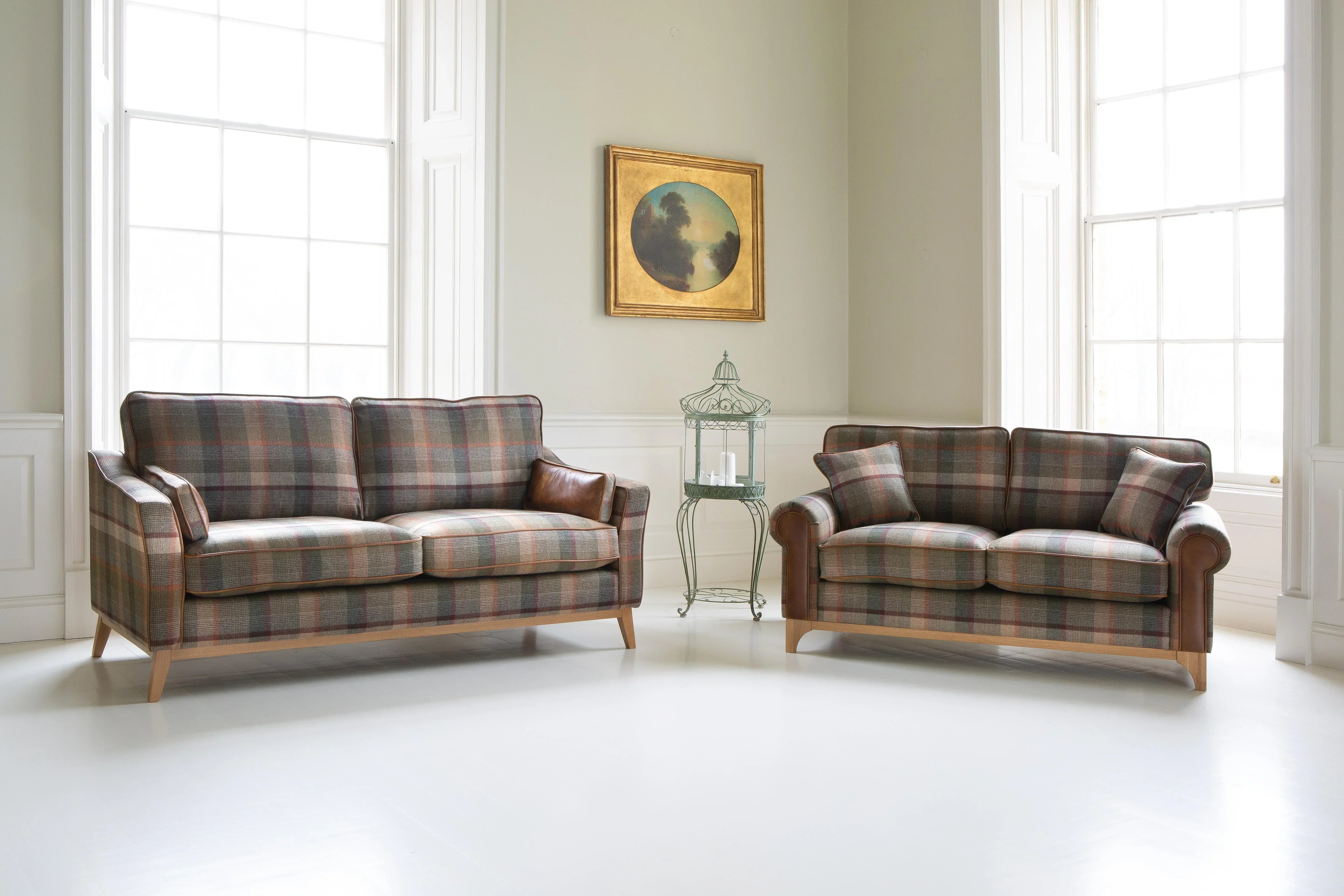 Plaid fabric sofas with leather armrests in bright lounge with large windows