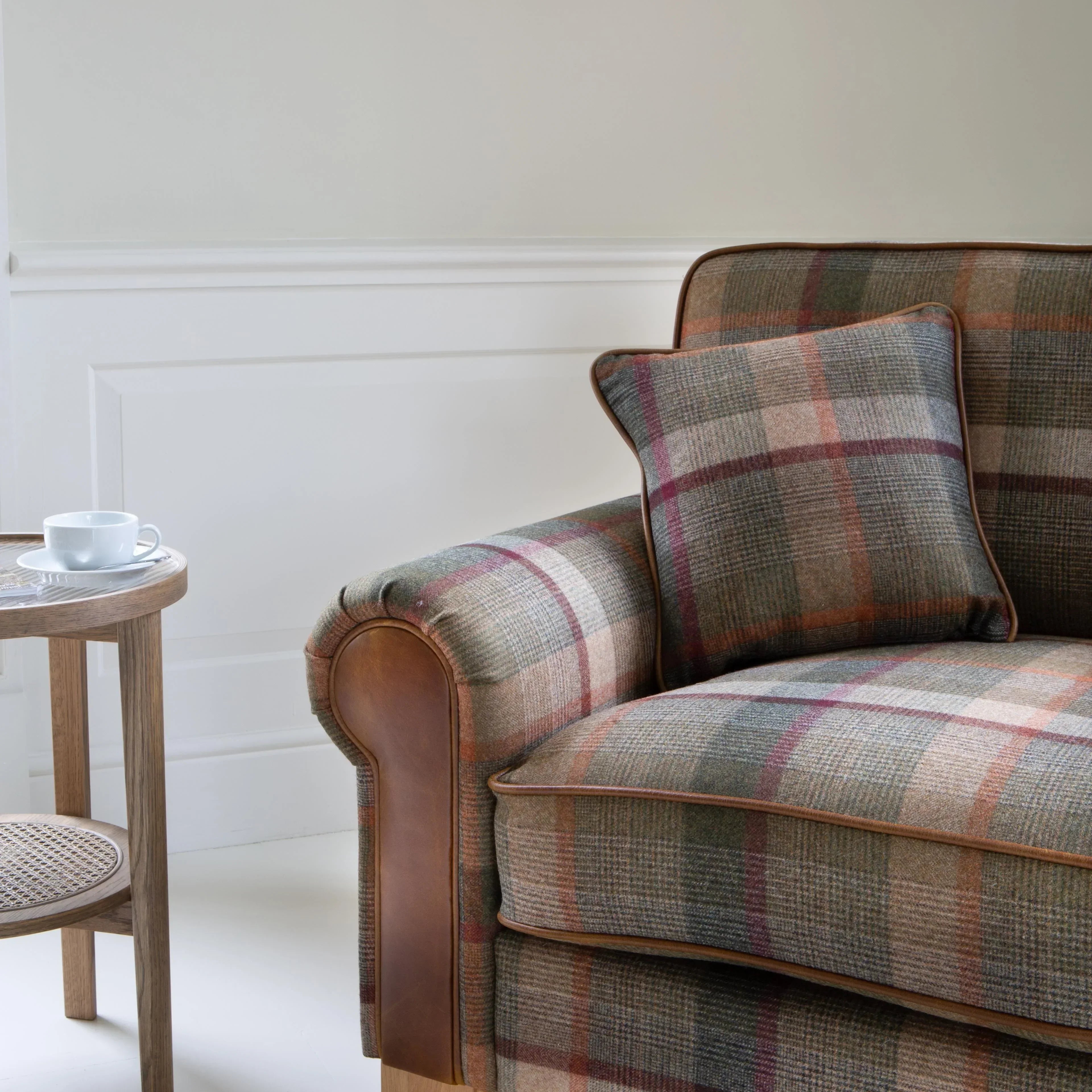 Plaid fabric sofa with matching cushion and wooden legs next to round side table