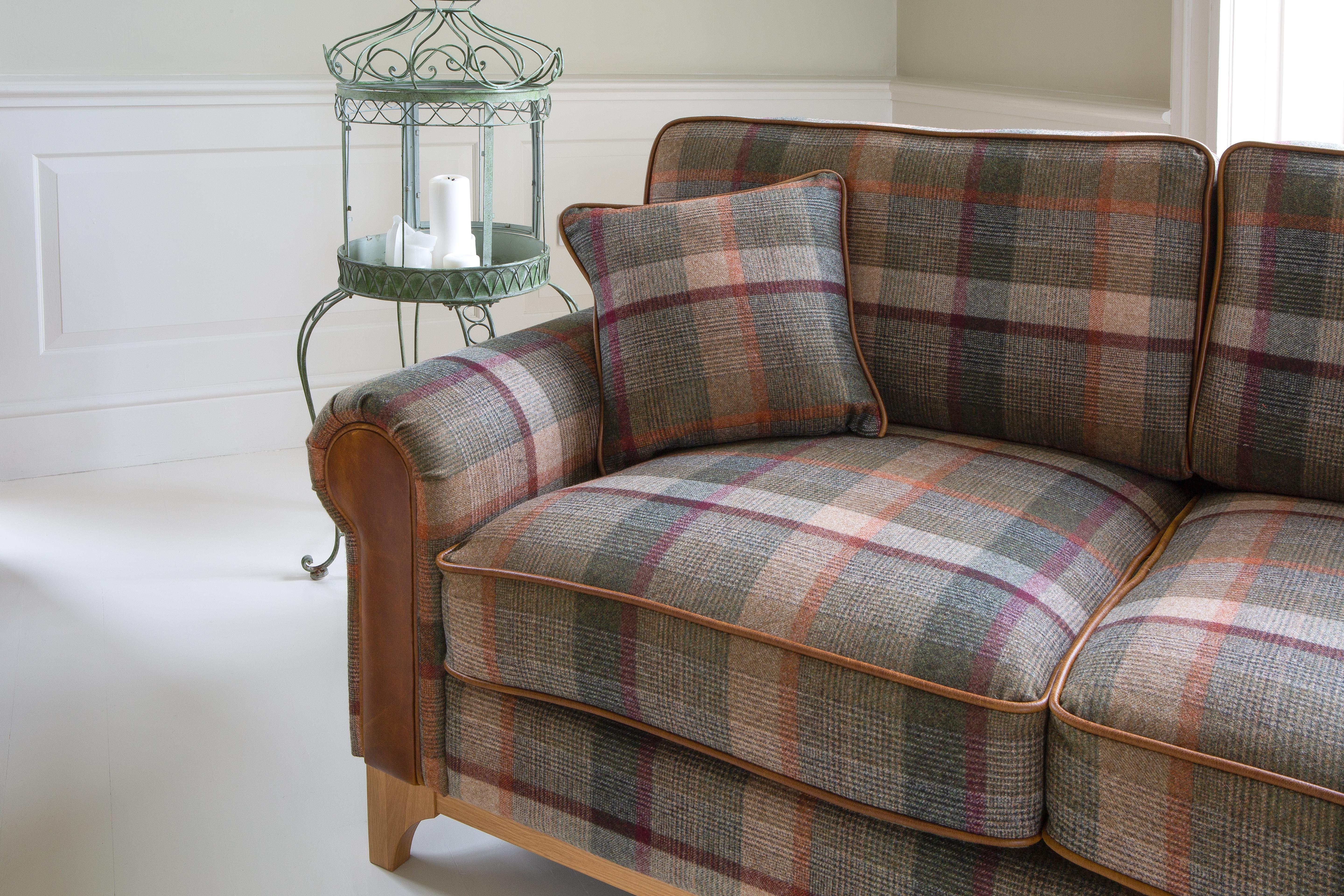 Plaid fabric sofa with brown leather arm detail and matching cushion in a bright living room