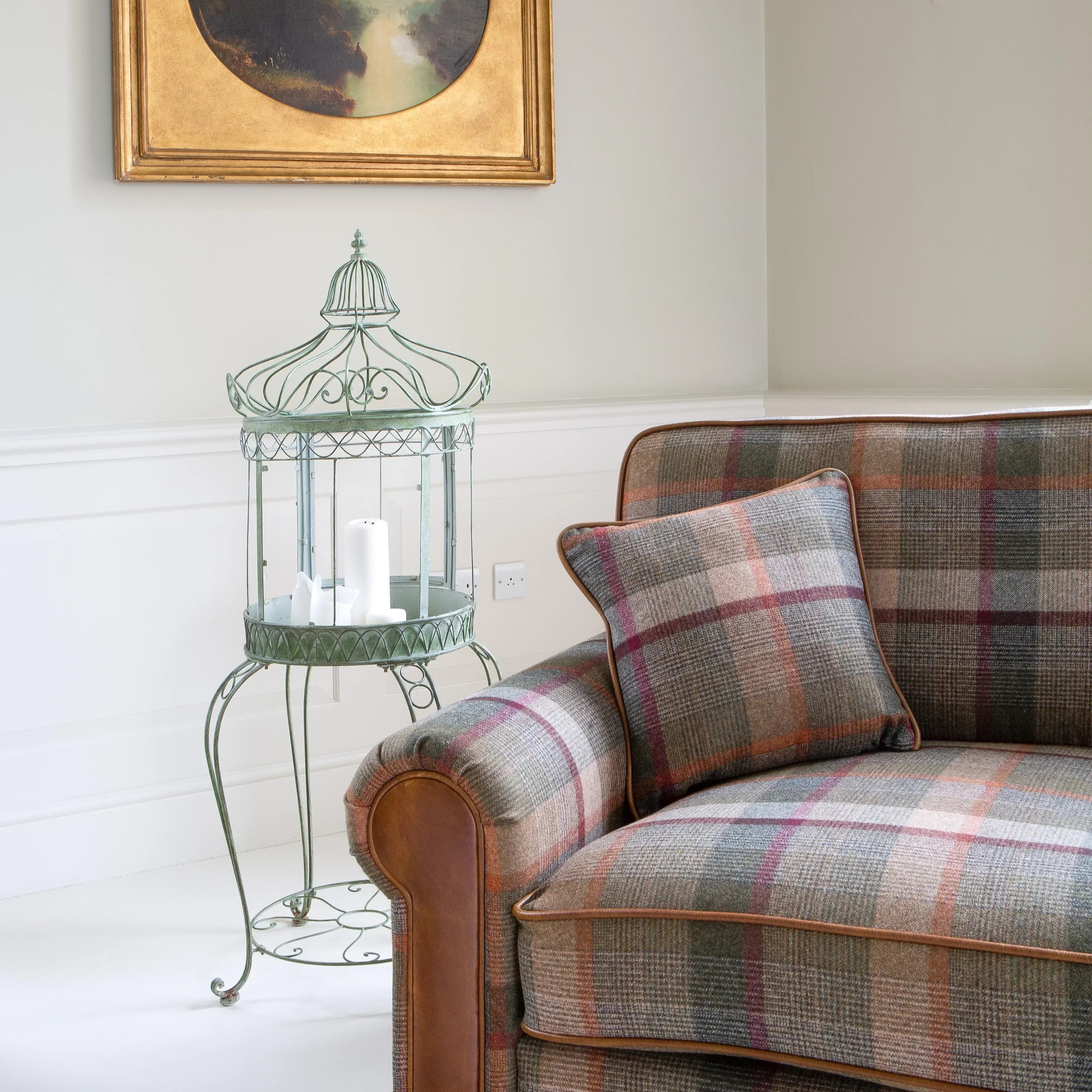 Plaid fabric sofa with leather armrests and cushion in bright living room corner