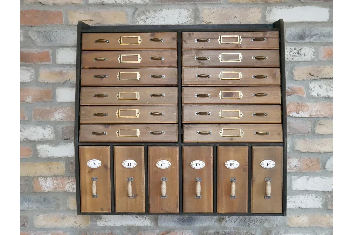Wall-mounted wooden storage cabinet with labeled drawers and brass handles