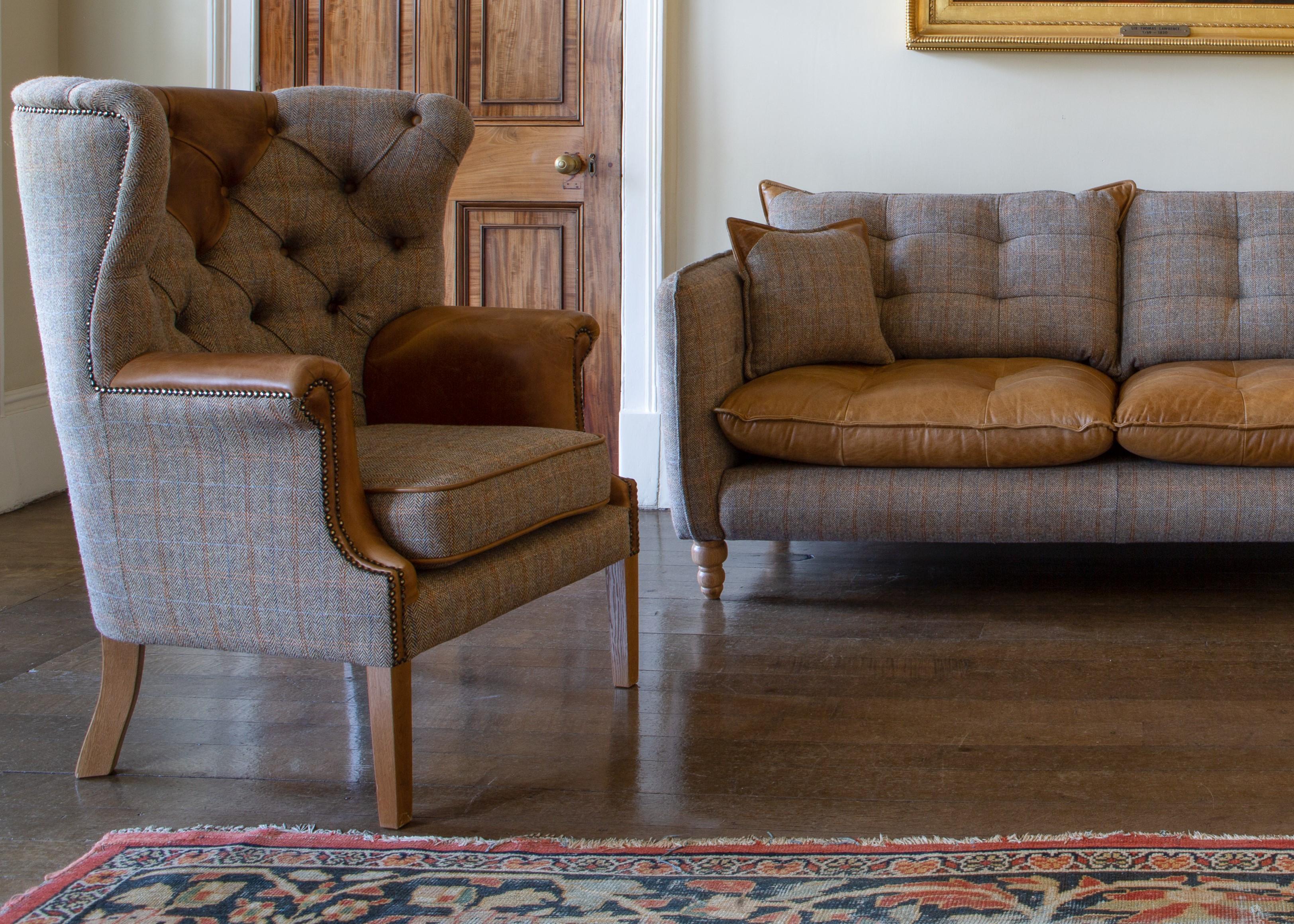 Plaid armchair and leather seat sofa set on wooden floor with patterned rug