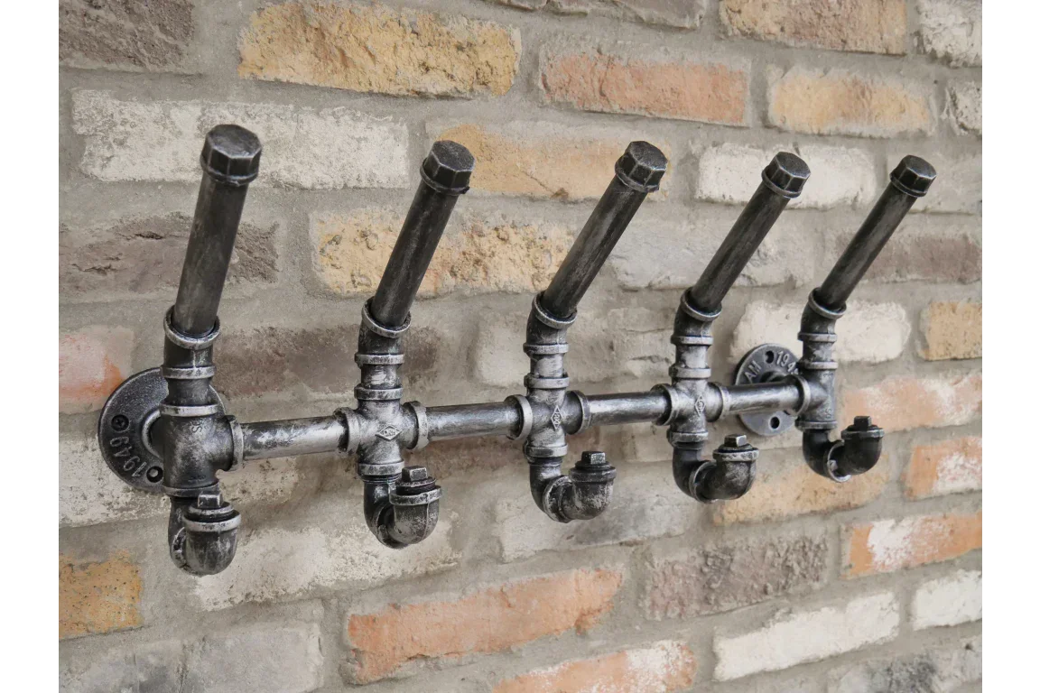 Industrial pipe wall coat rack with five hooks mounted on brick wall