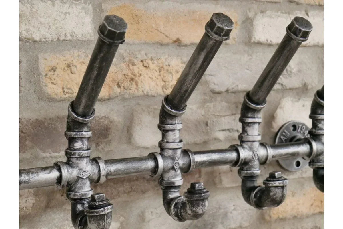 Industrial metal coat hooks in pipe design mounted on exposed brick wall