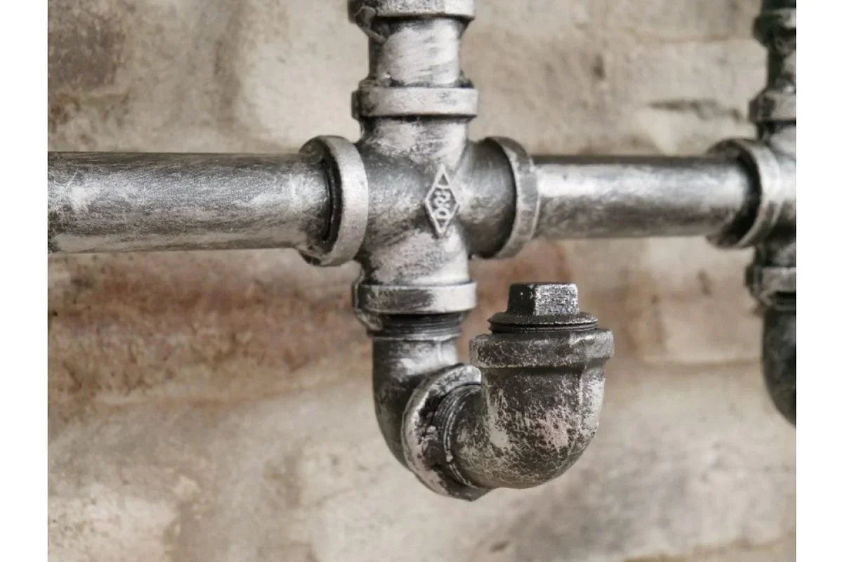 Industrial metal pipe detail with textured grey finish on exposed brick wall