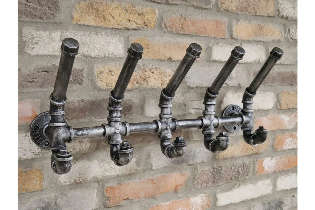 Industrial metal coat rack with five pipe hooks mounted on exposed brick wall