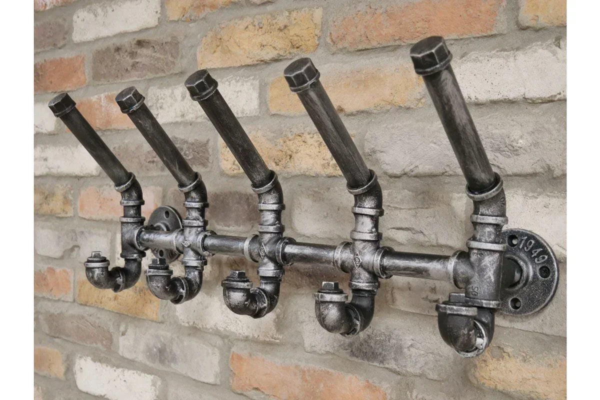 Industrial pipe coat rack with four hooks mounted on exposed brick wall