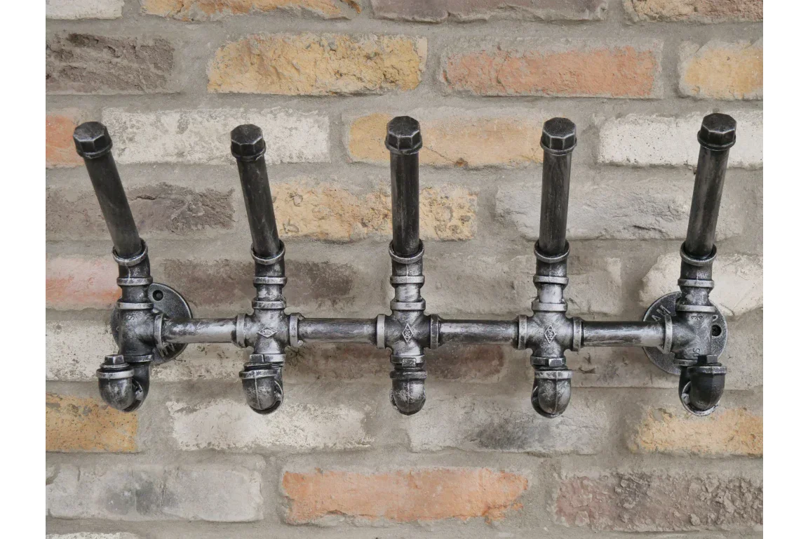 Industrial pipe coat rack with five hooks mounted on exposed brick wall