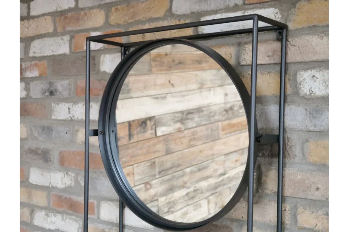 Round wall mirror with black metal frame mounted on exposed brick wall