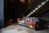 Patchwork fabric sofa with wooden legs in a traditional hallway next to staircase