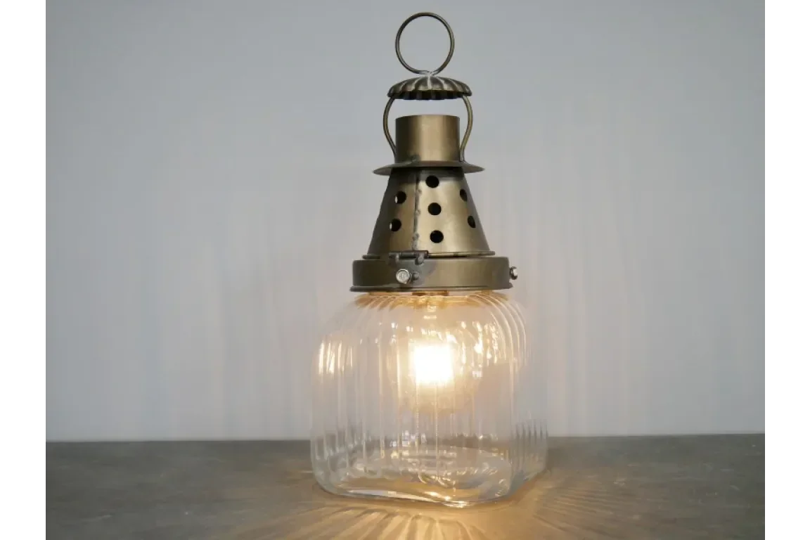 Vintage glass table lantern with brass metal top and glowing light bulb