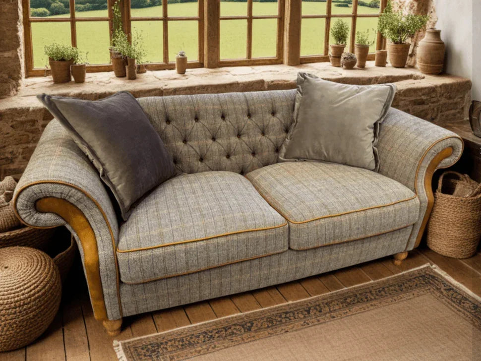 Grey fabric sofa with button-tufted back, yellow trim, two cushions, rustic room setting