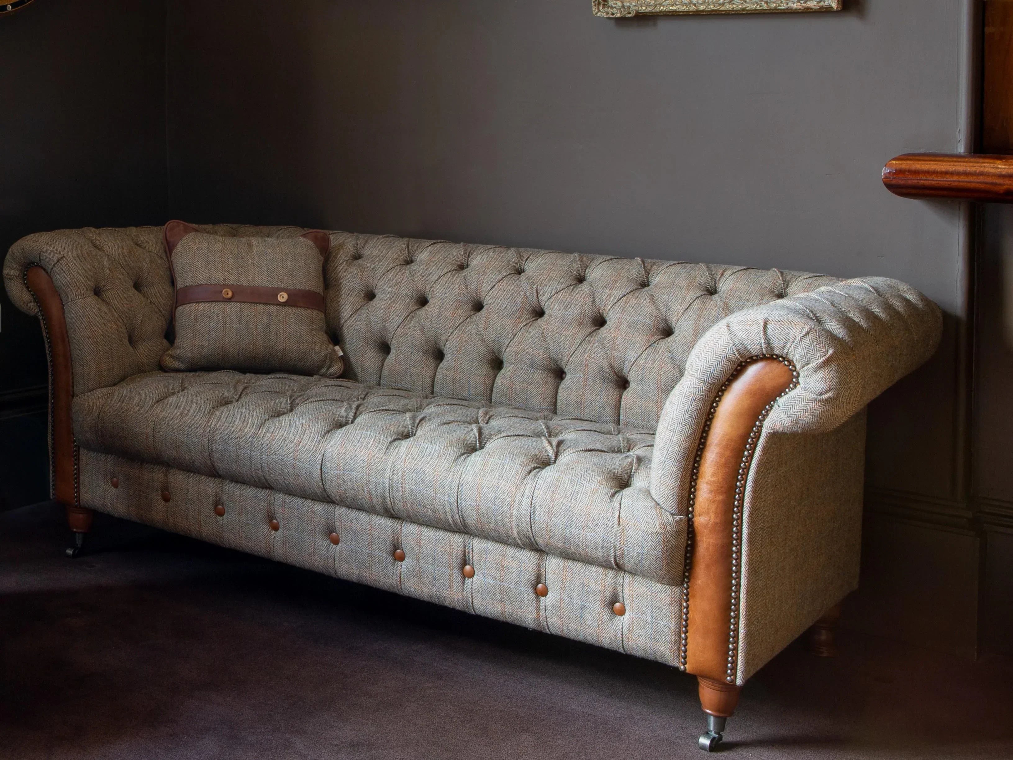 Tufted tweed chesterfield sofa with brown leather accents and button details in living room