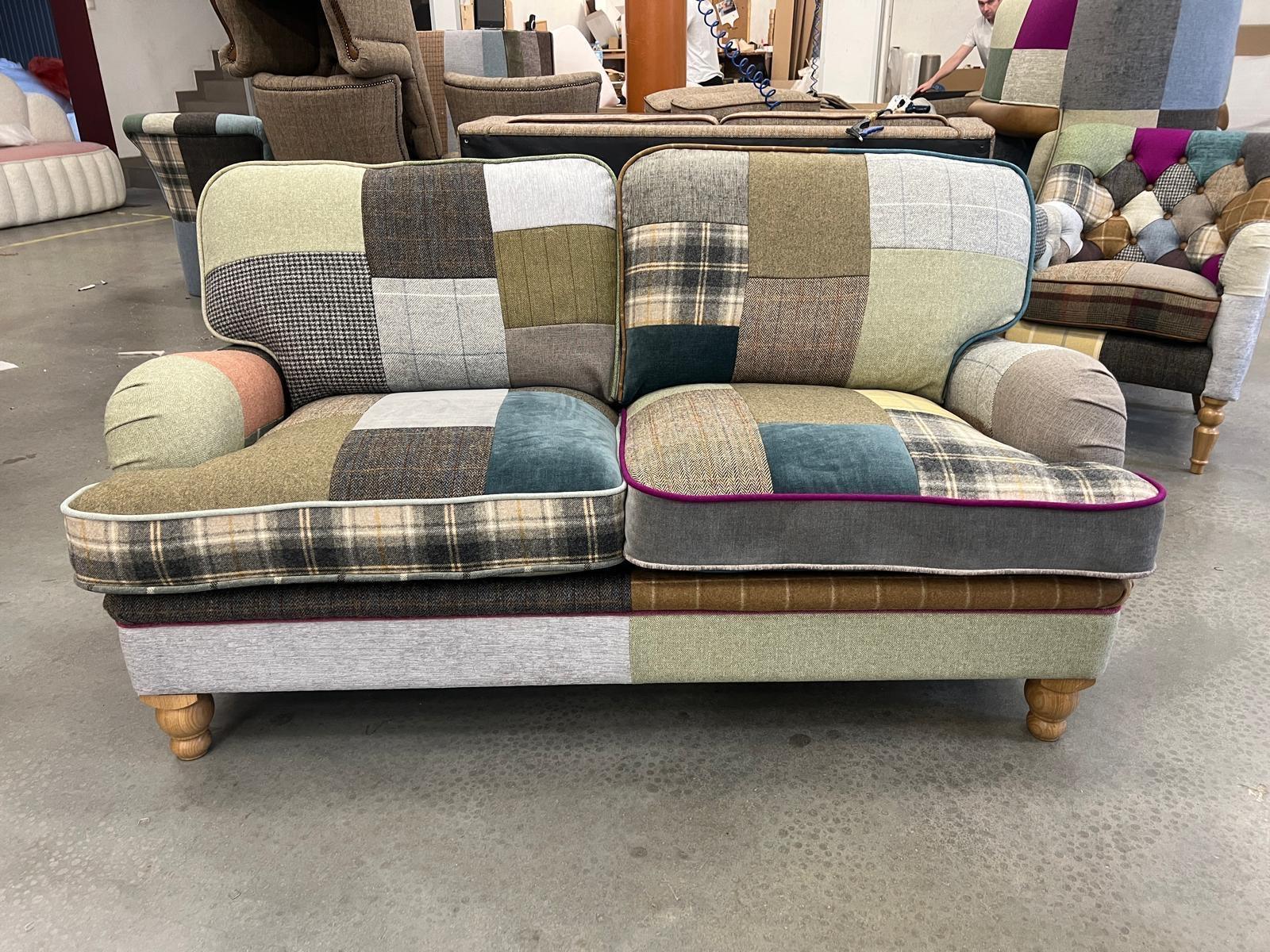 Patchwork fabric sofa with plaid and solid panels, wooden legs, two seat cushions, indoor setting
