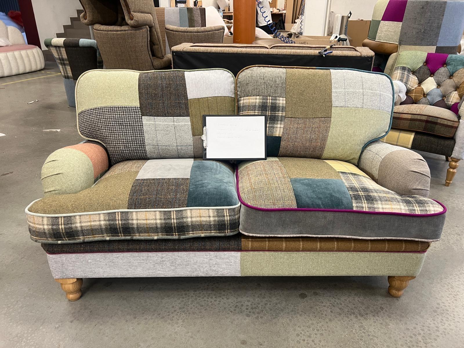 Patchwork fabric sofa with wooden legs and piped edges, two seat design in showroom setting