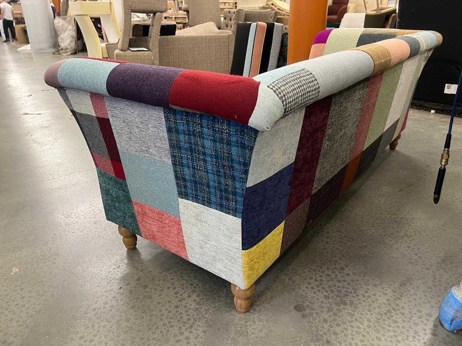 Patchwork fabric sofa with wooden legs, shown from a rear angle in showroom