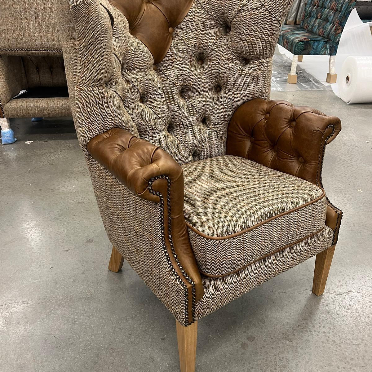Tufted high back armchair with brown leather trim and herringbone fabric upholstery