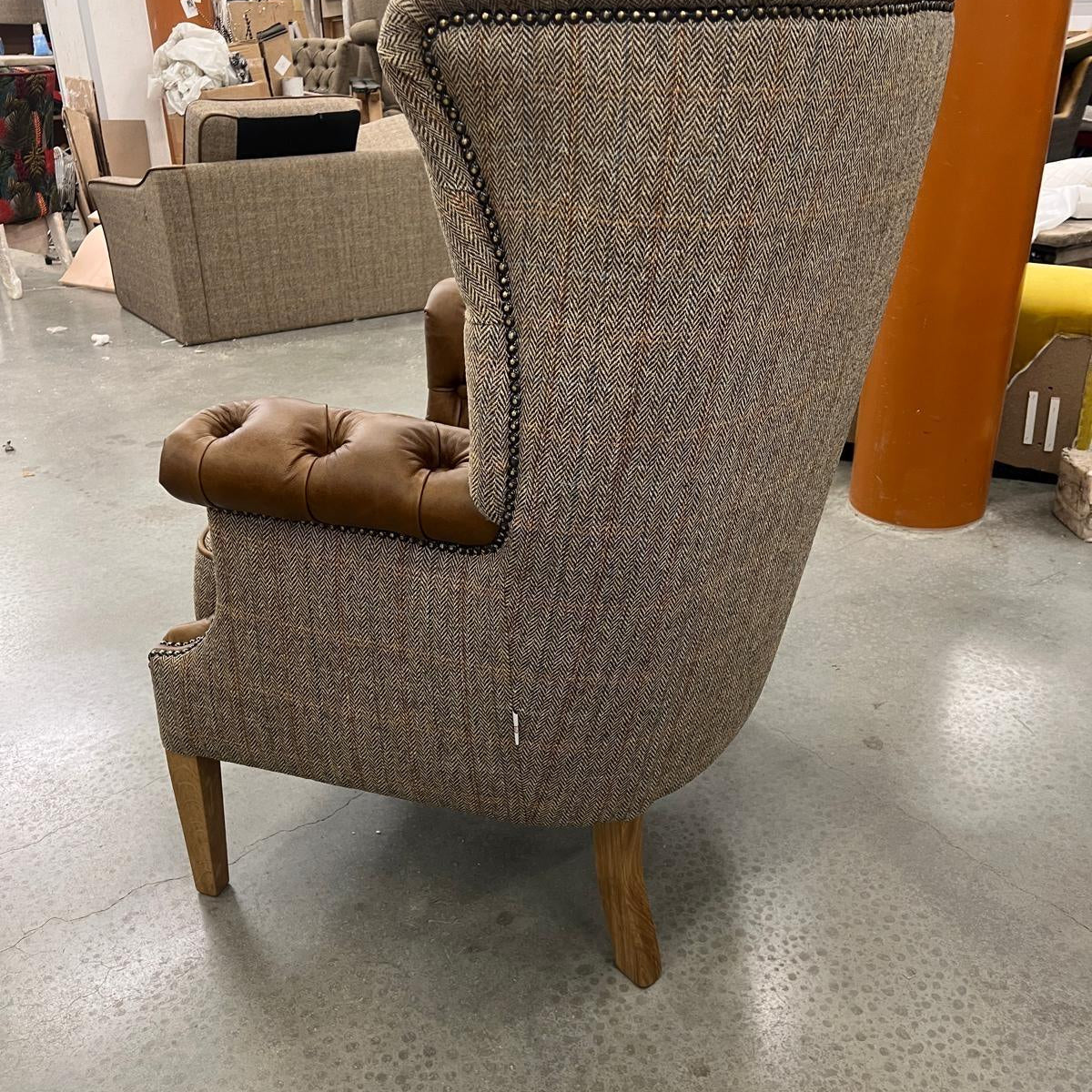 Herringbone fabric armchair with brown leather trim and buttoned seat, rear side view