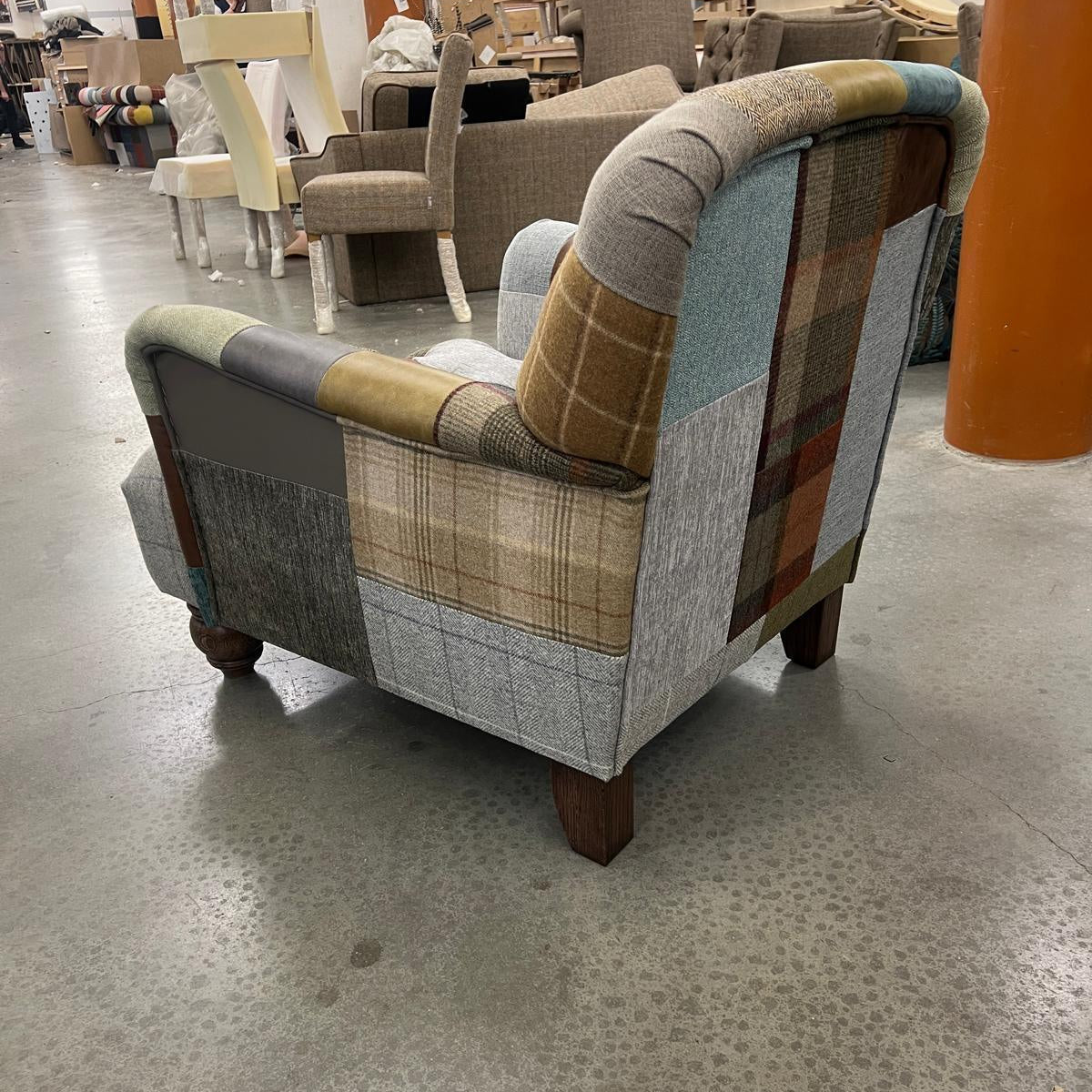 Patchwork armchair with wooden legs in furniture workshop setting
