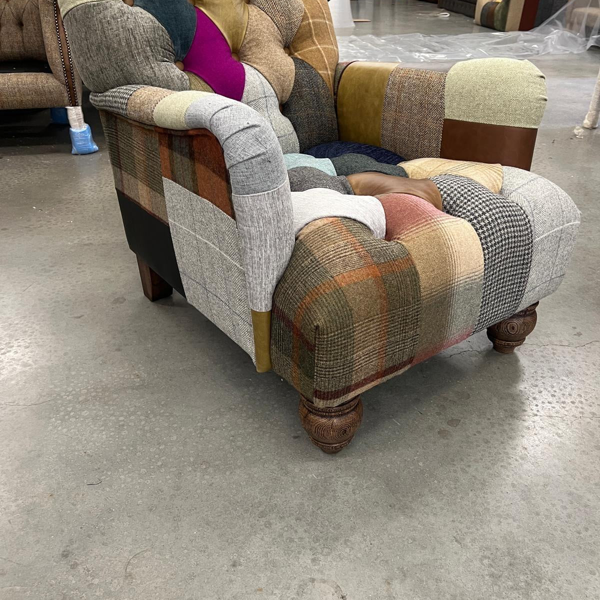 Patchwork upholstered armchair with tufted backrest and wooden carved legs on showroom floor